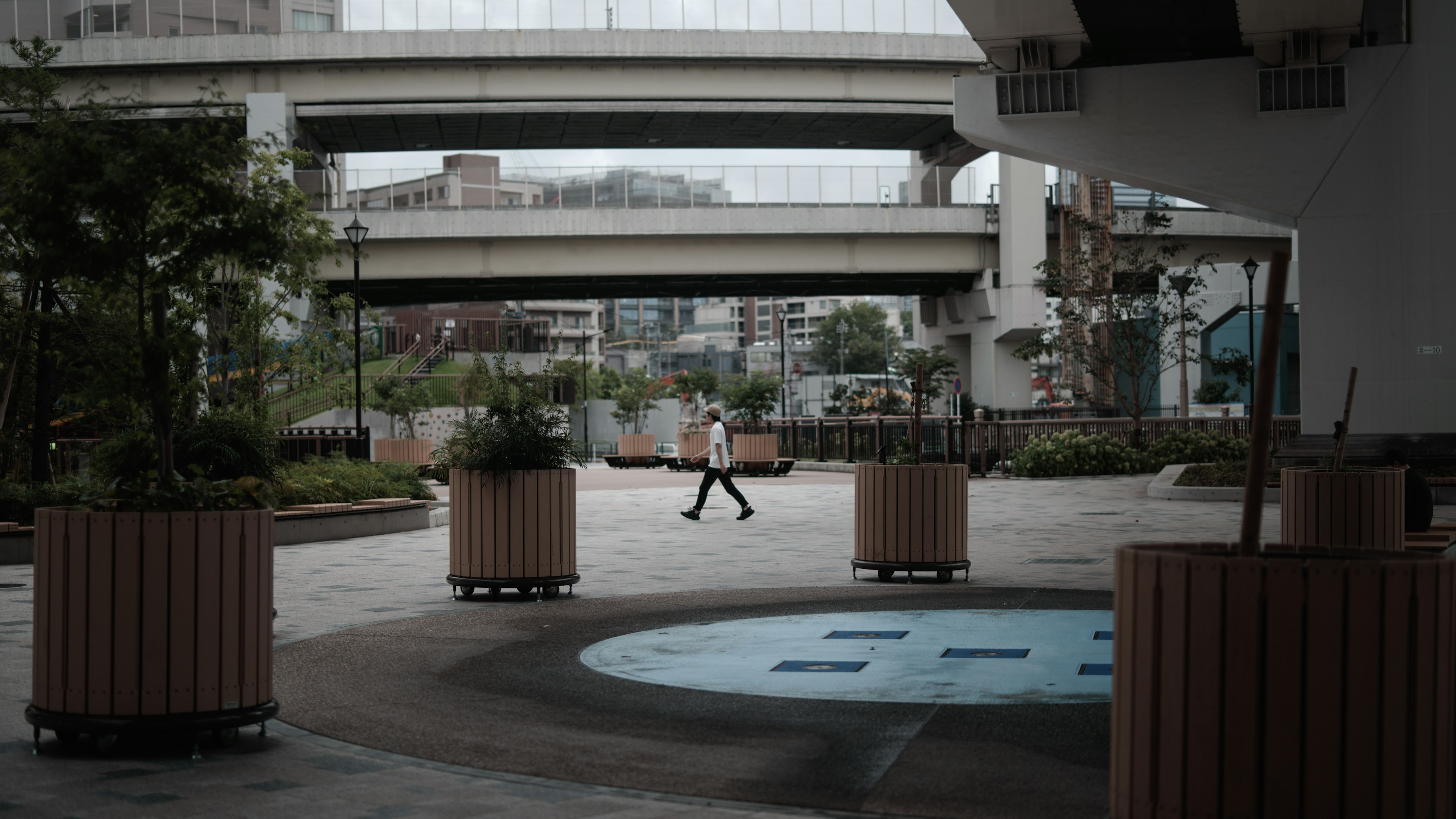 Scena di parco urbano con una persona che cammina tra vasi e vegetazione