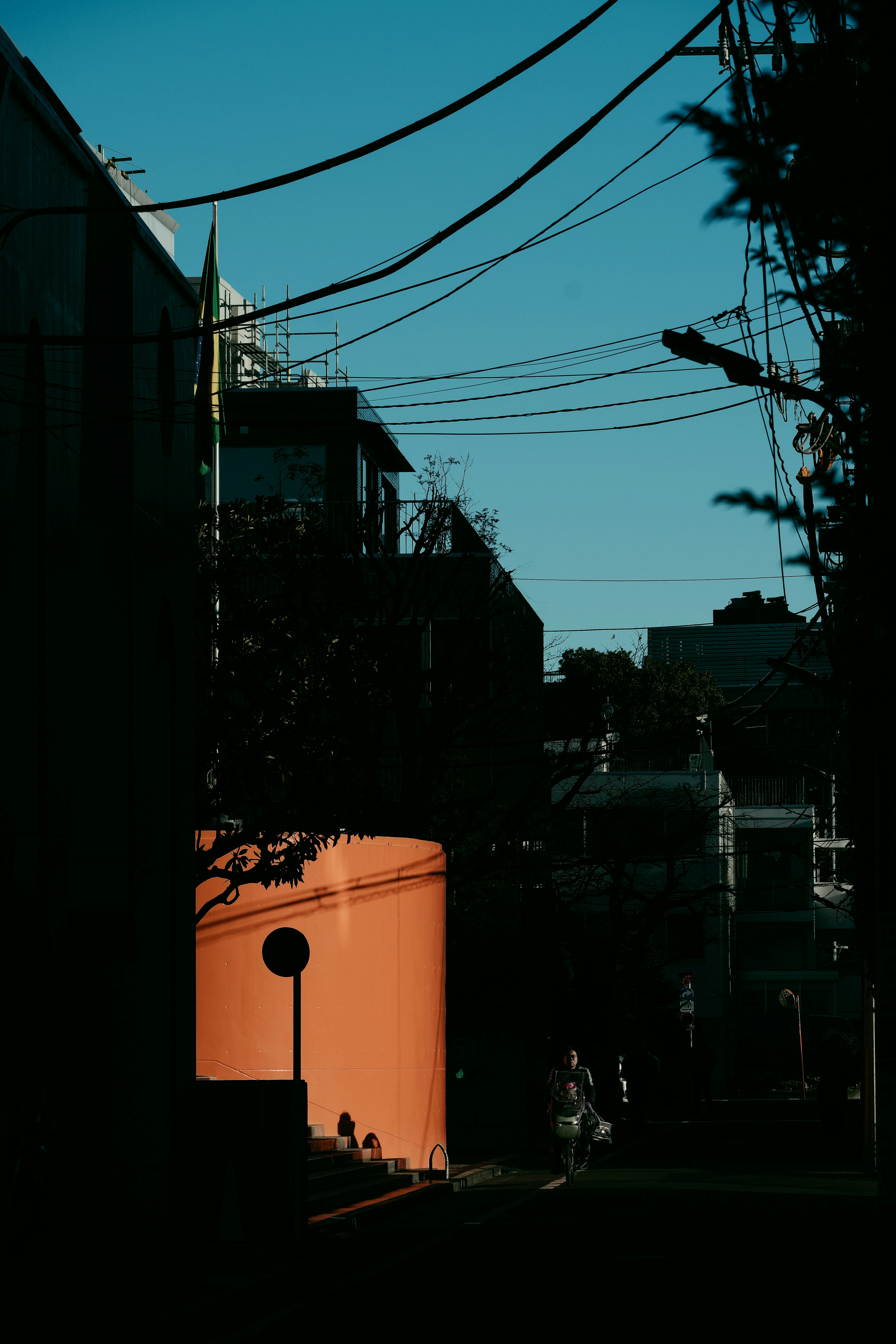 Escena de calle bajo un cielo azul con una pared naranja