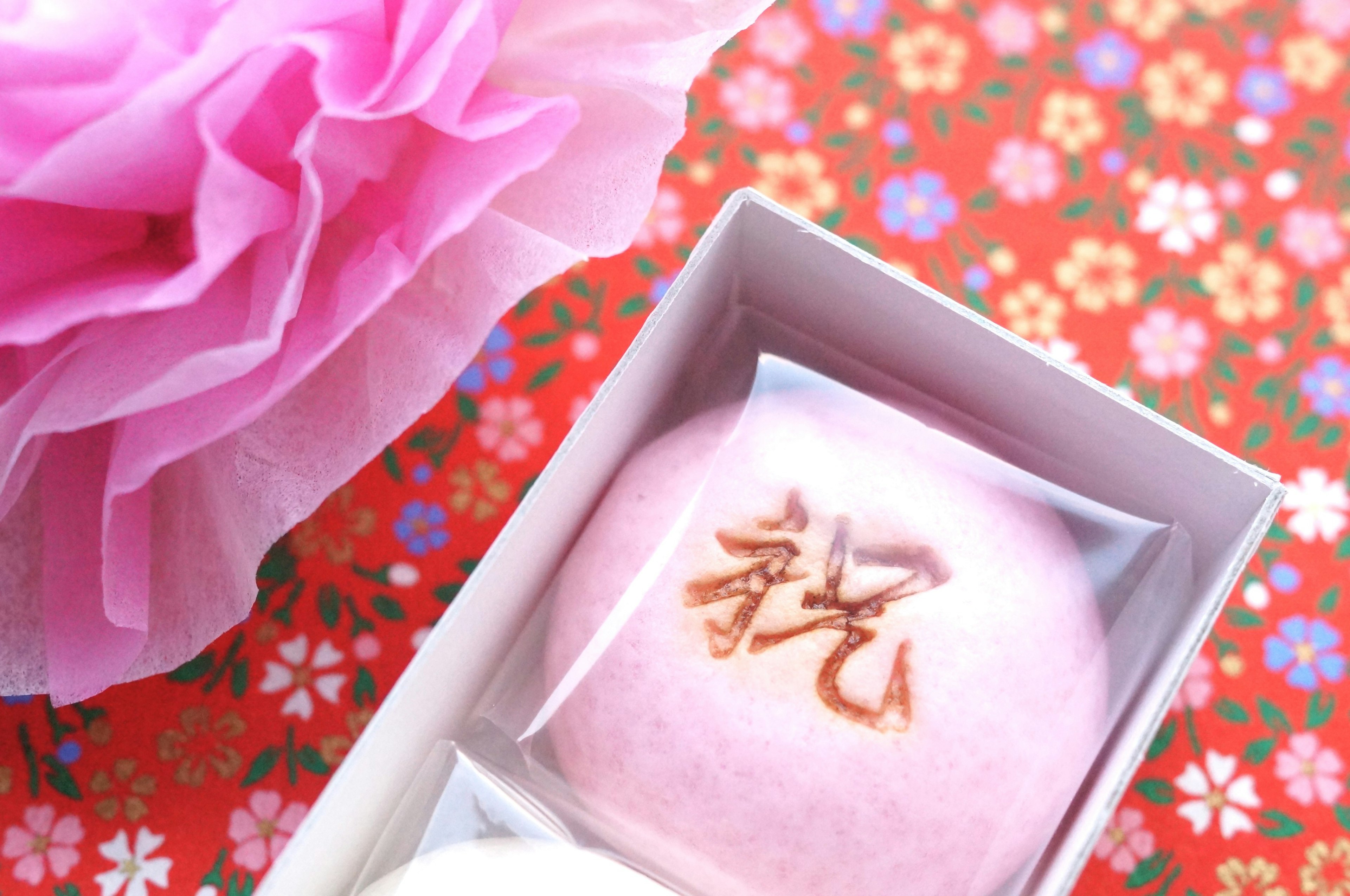 Pink Japanese confection with kanji on it against a floral background