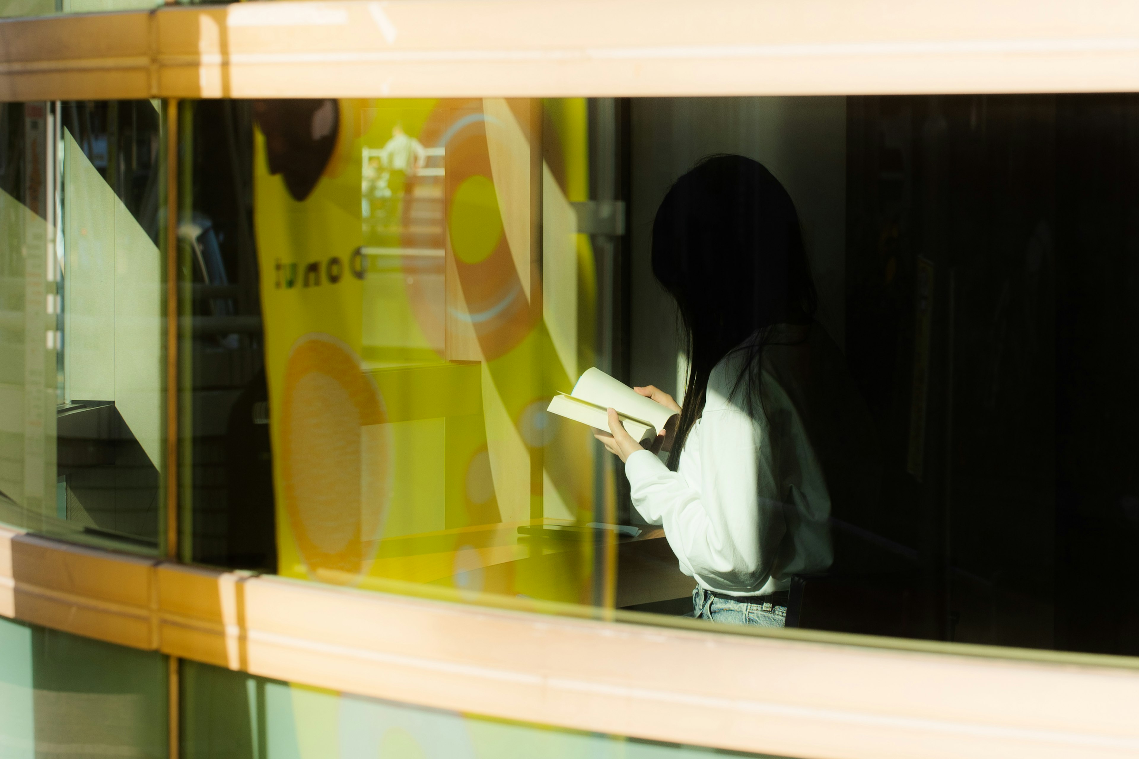 A silhouette of a woman reading a book against a colorful background