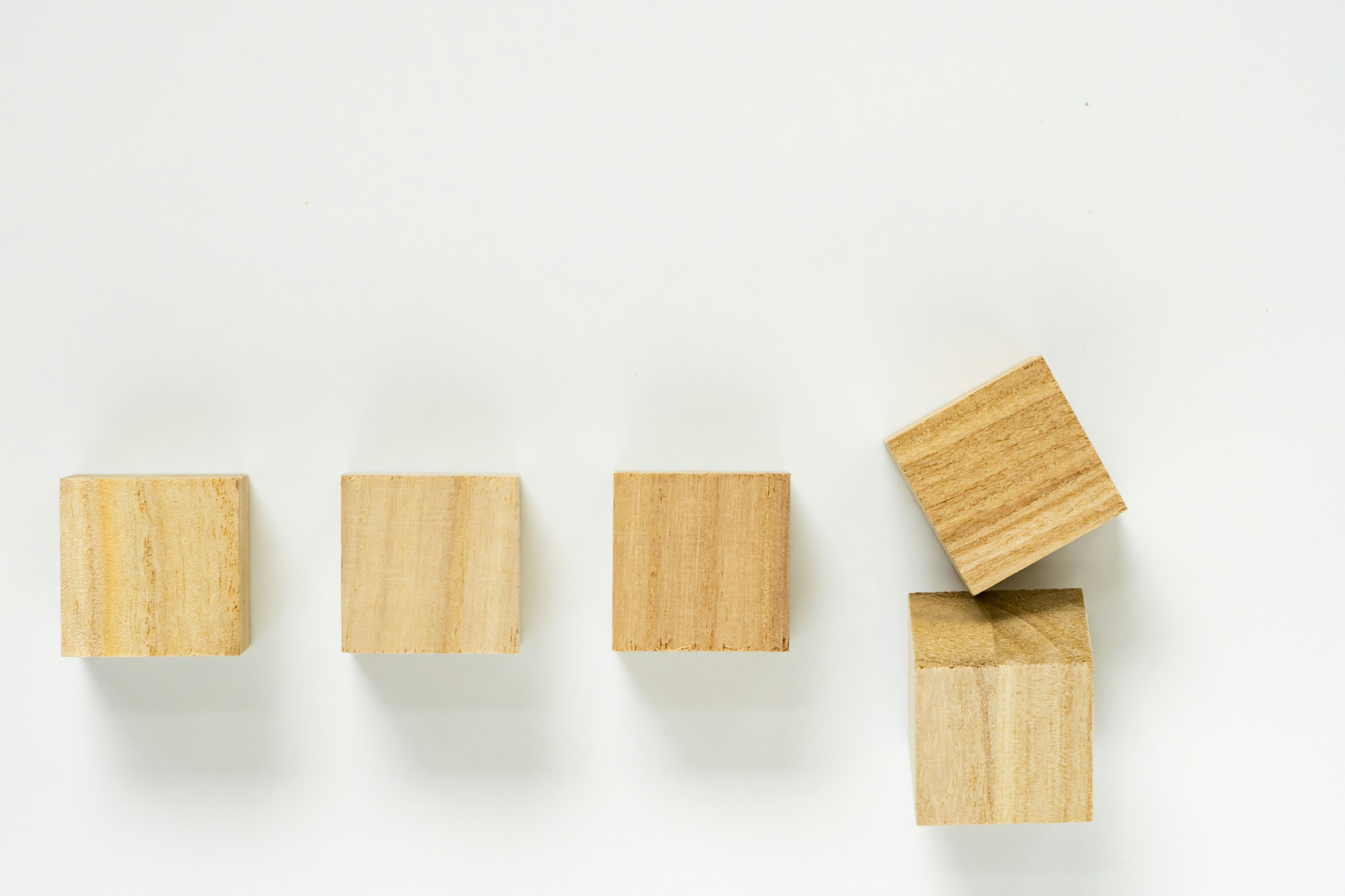 Una serie di blocchi di legno disposti su uno sfondo bianco con un blocco impilato