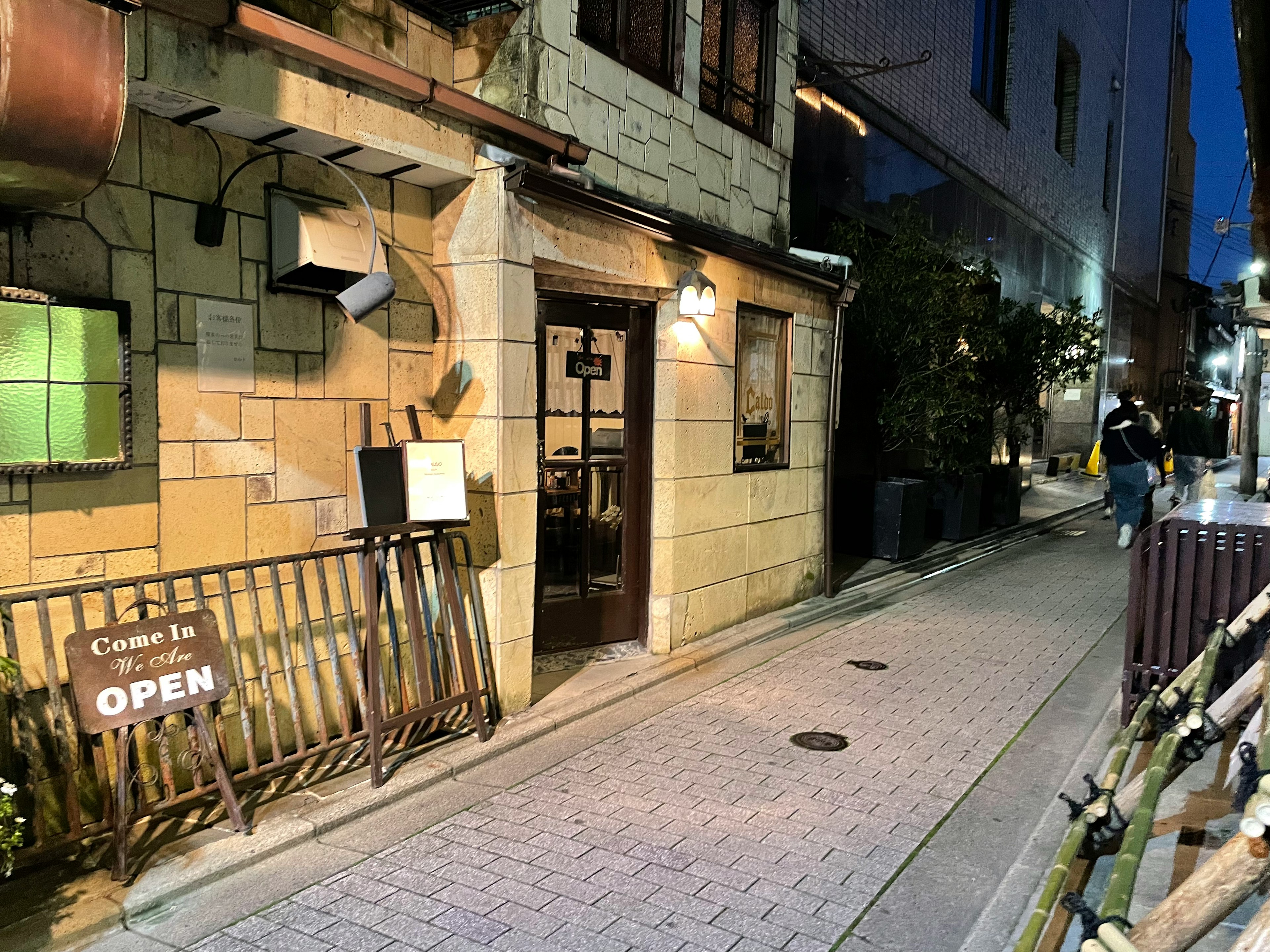 Exterior de un restaurante con un cartel de abierto en una esquina de la calle por la noche