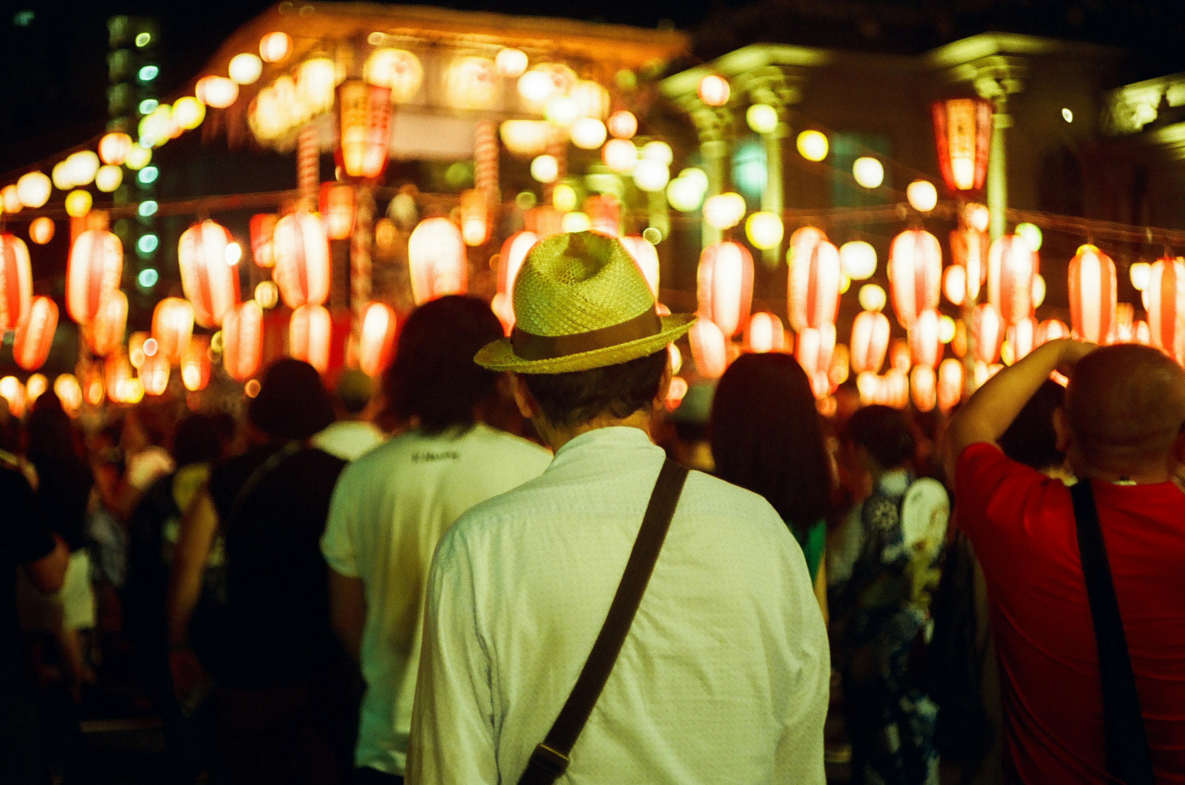 Orang-orang berjalan di festival malam dengan lentera yang menyala