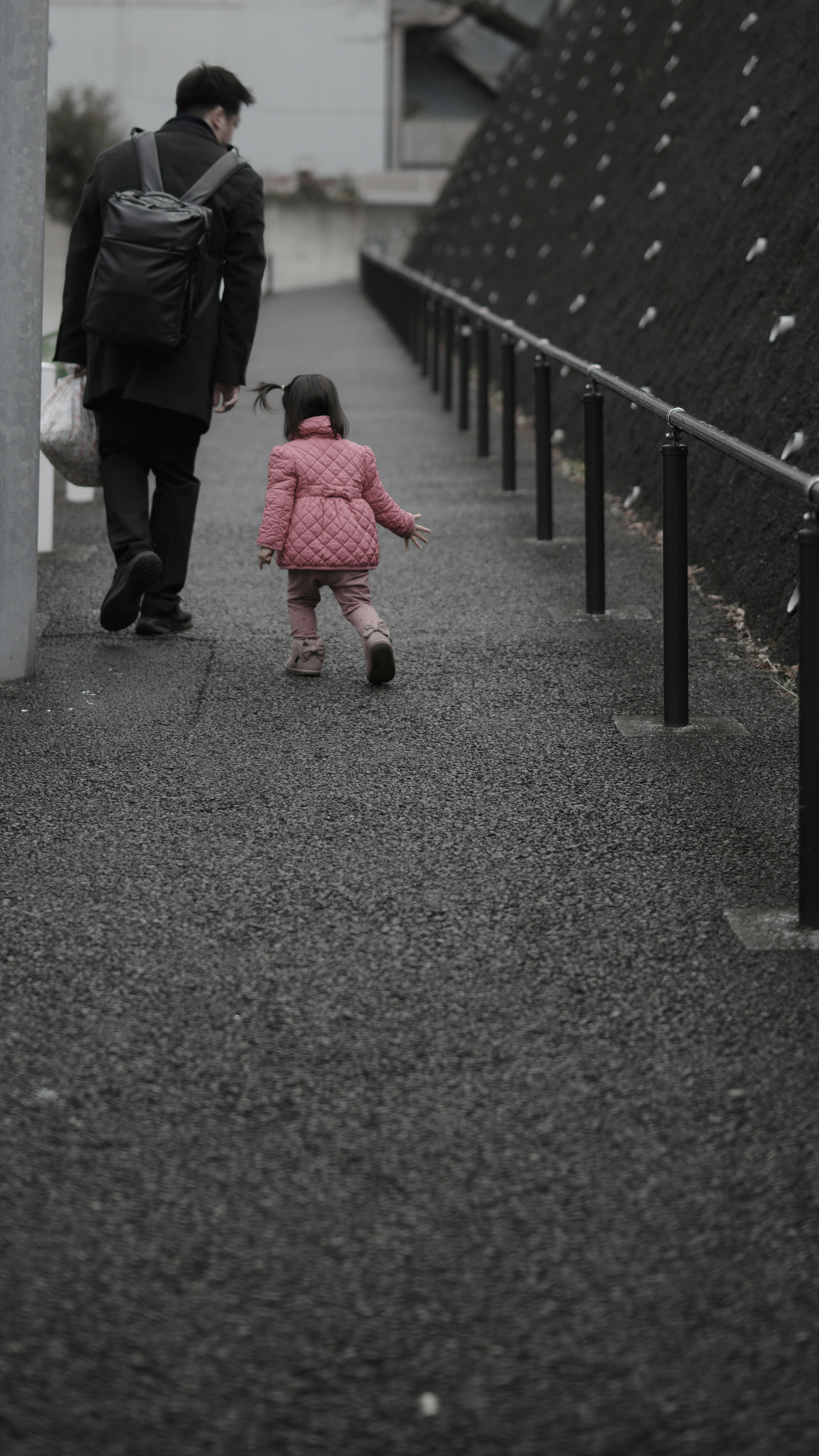 Un padre y una niña pequeña caminando por un camino en blanco y negro