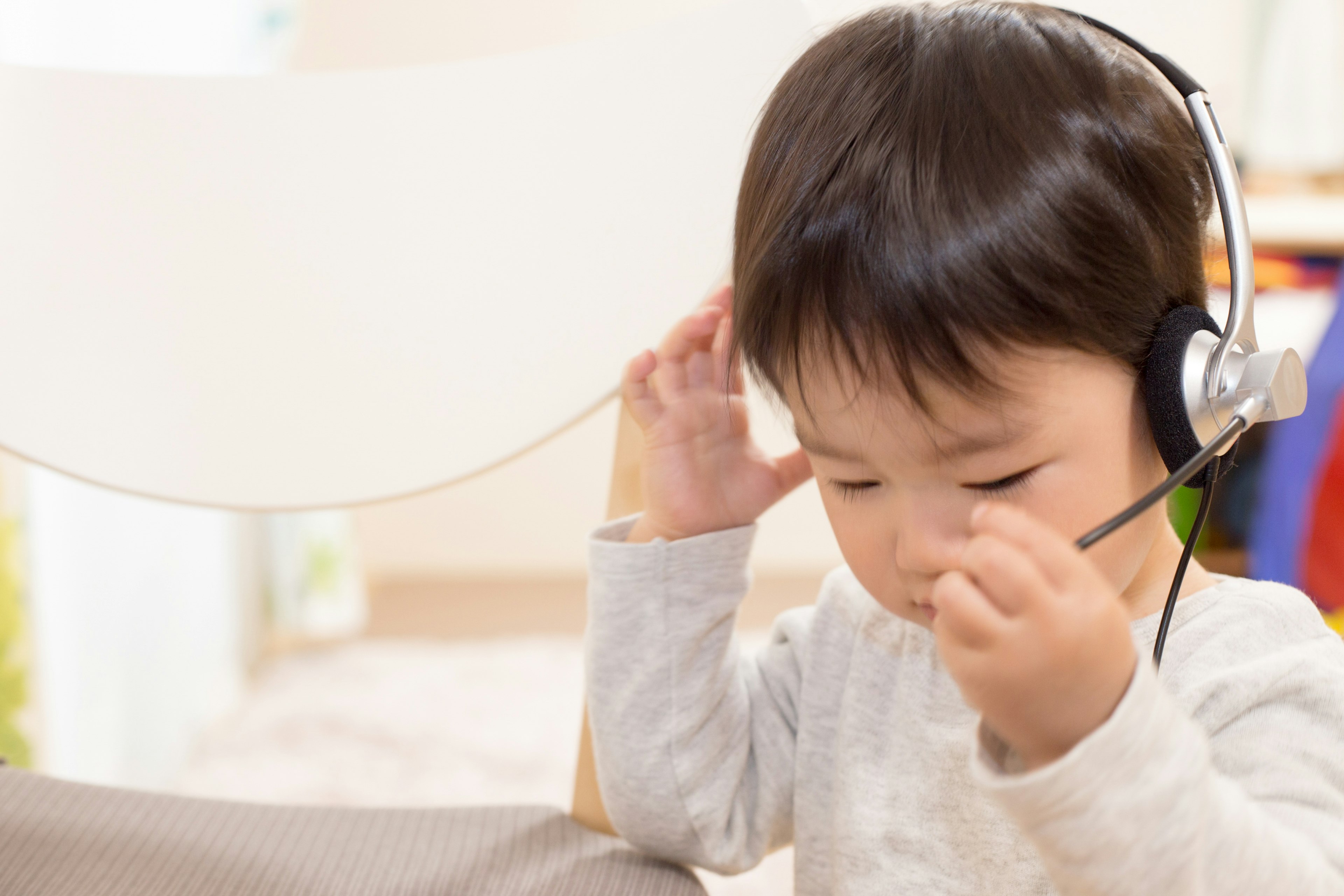 Seorang anak kecil mengenakan headphone fokus pada suatu aktivitas