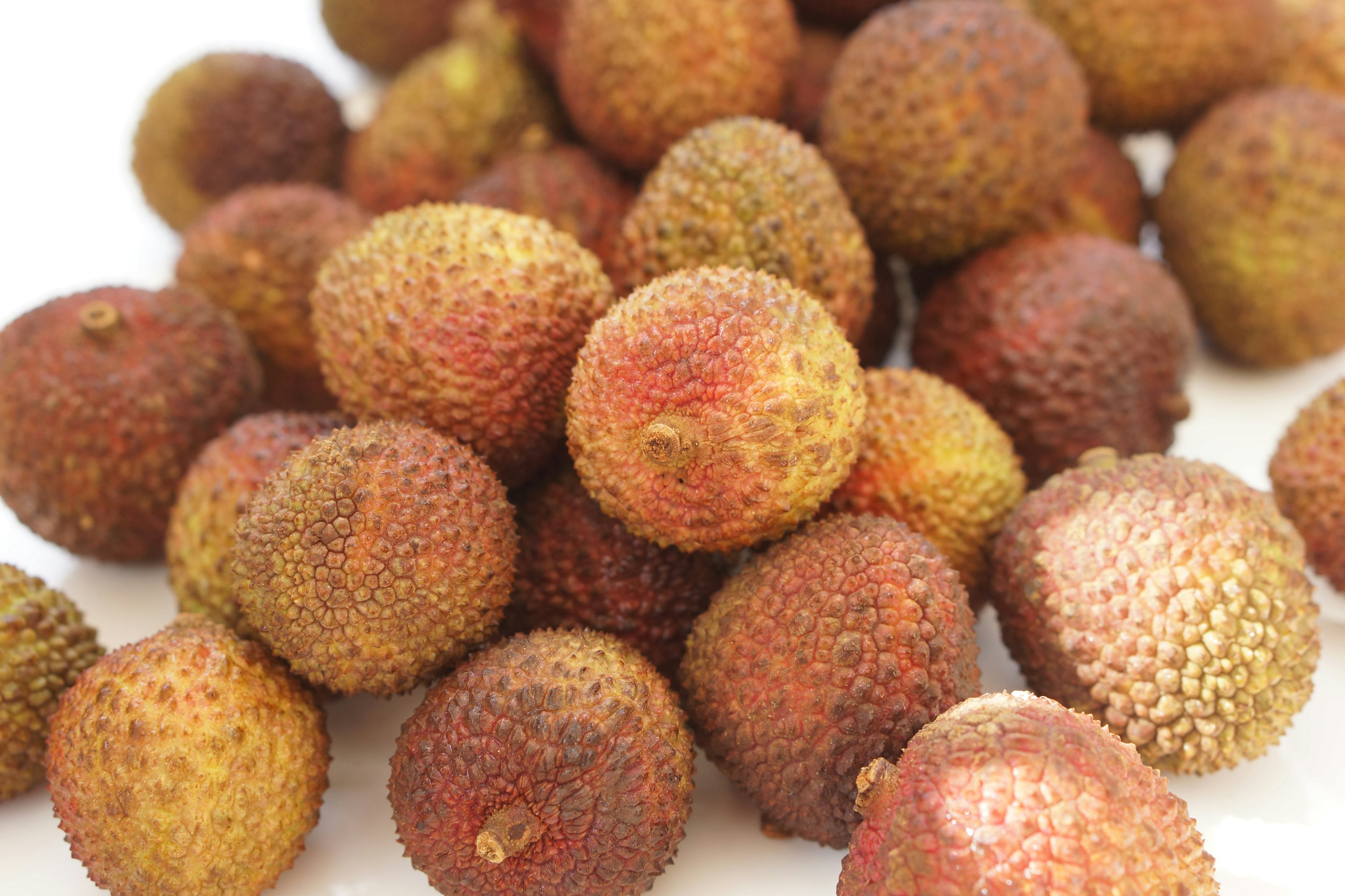 A pile of lychee fruits with a rough, reddish skin