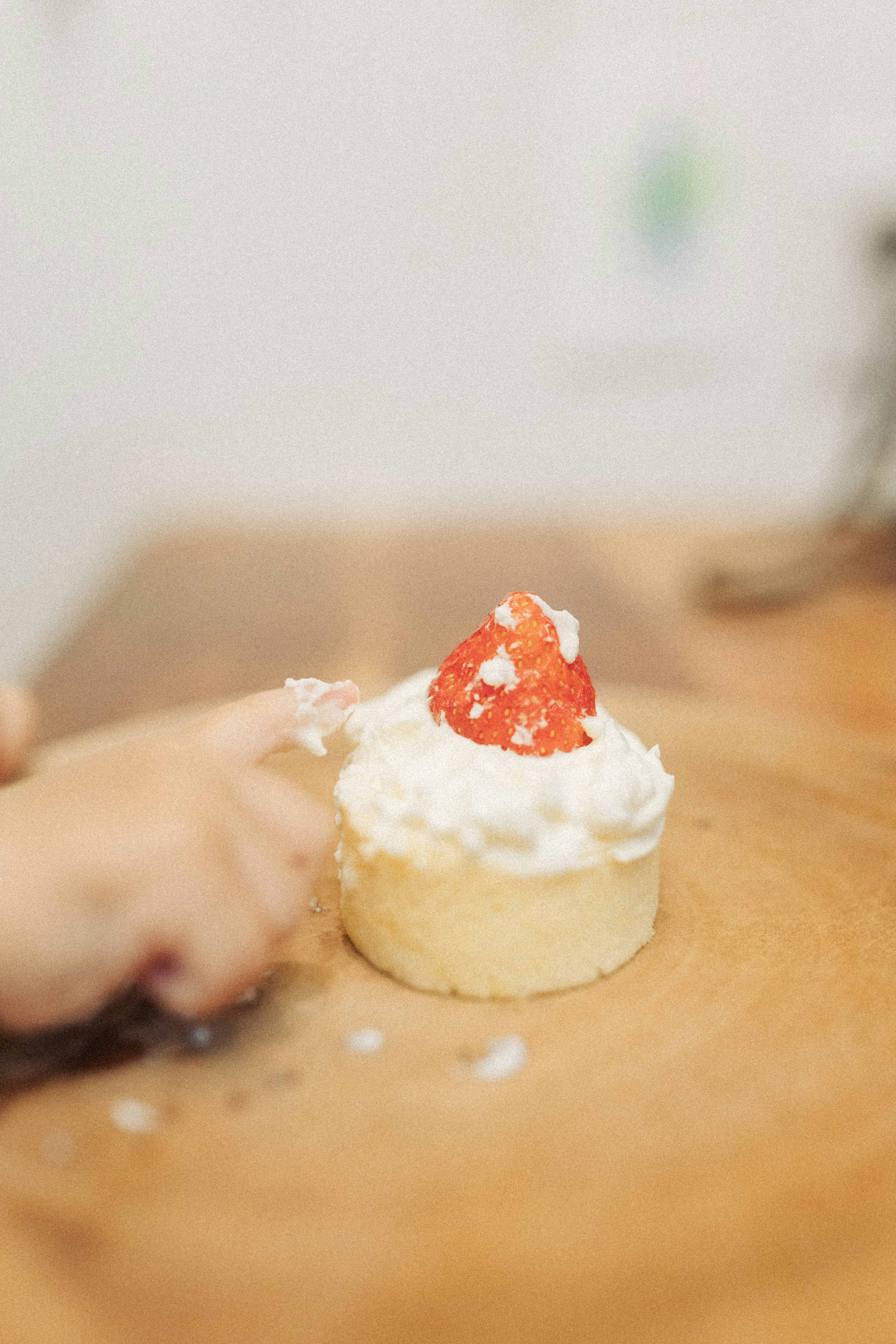 Un doigt touchant un cupcake garni de crème et d'une fraise