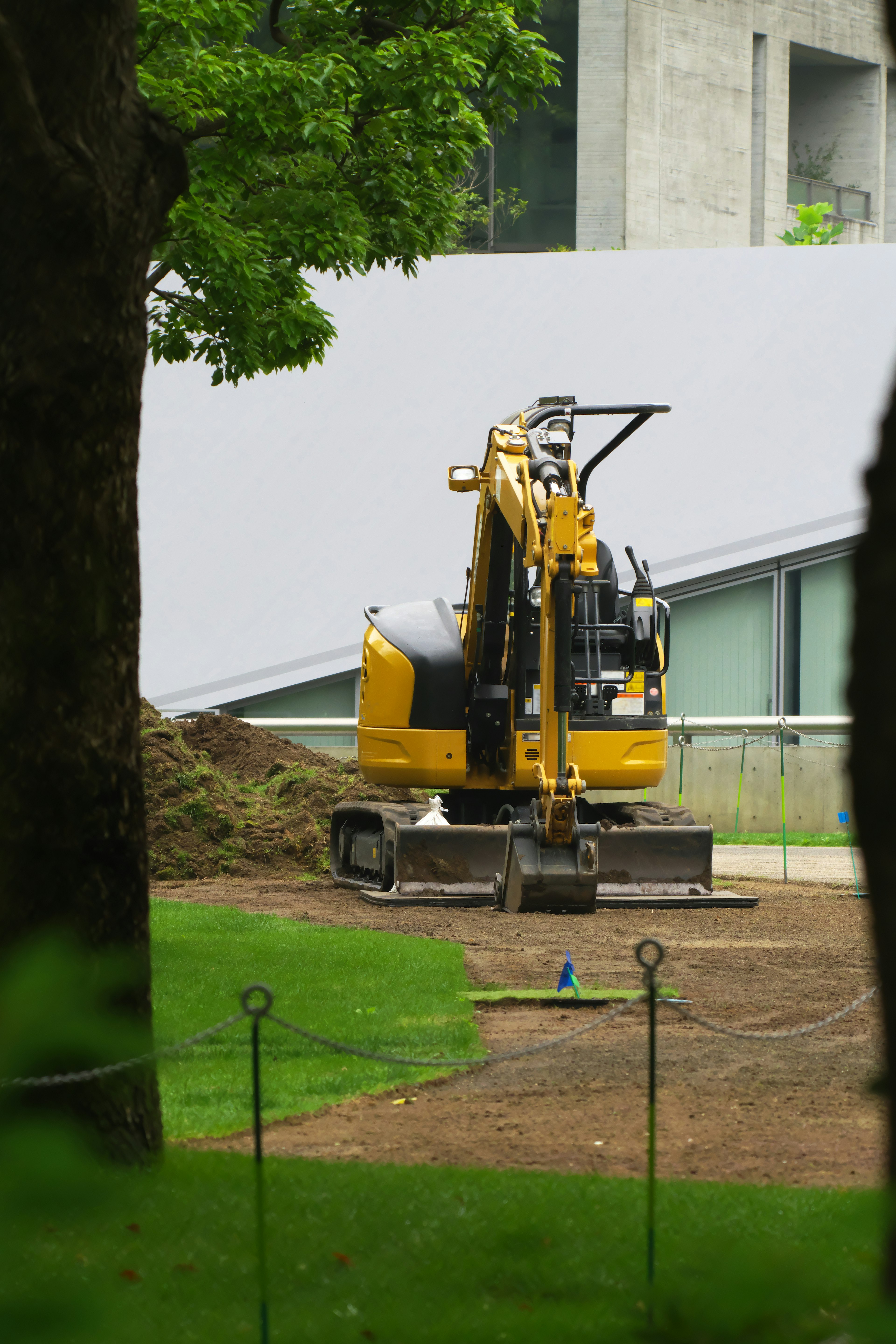 Excavatrice jaune travaillant sur une zone herbeuse verte