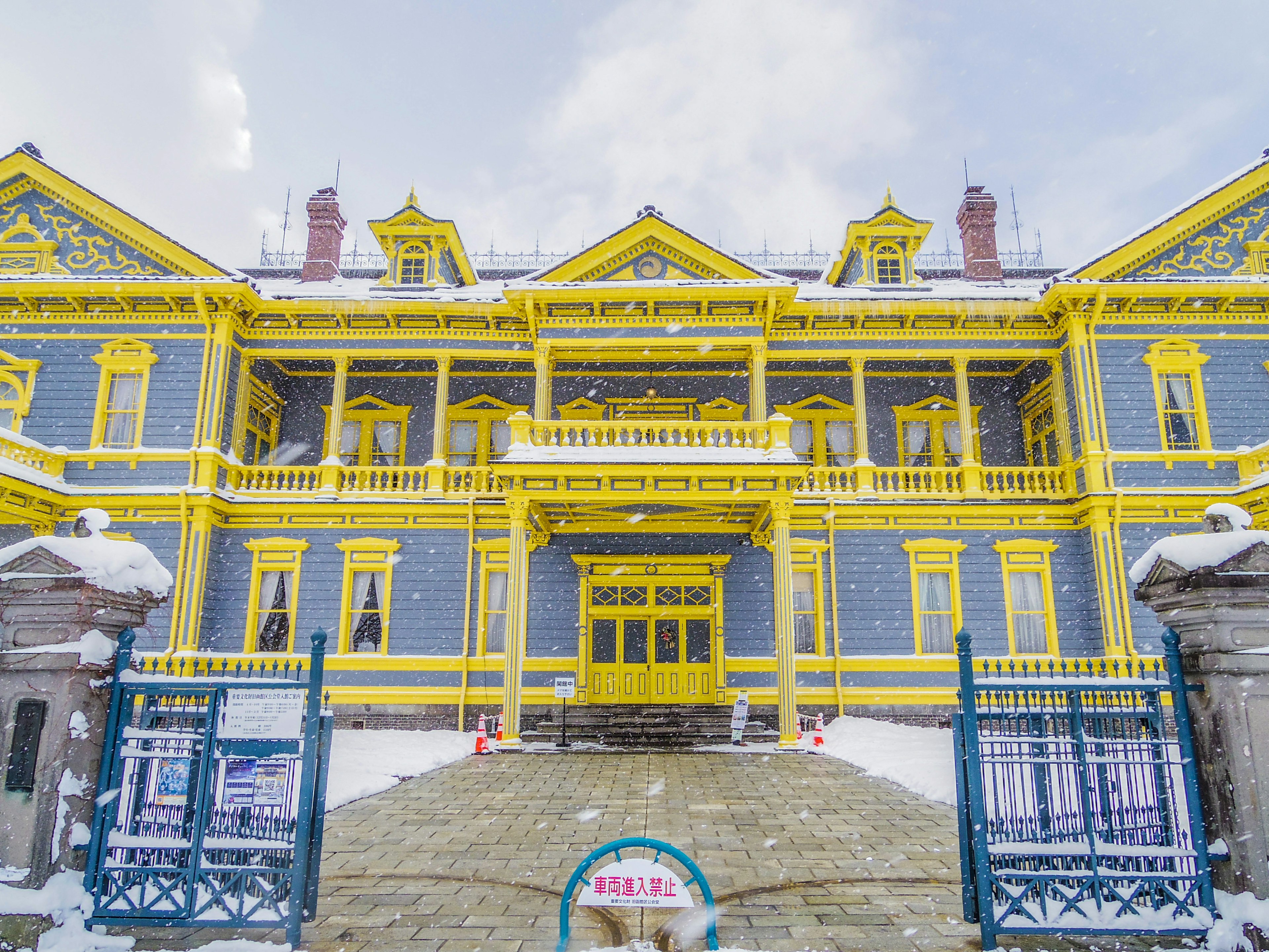 Fachada de un lujoso edificio azul y amarillo cubierto de nieve