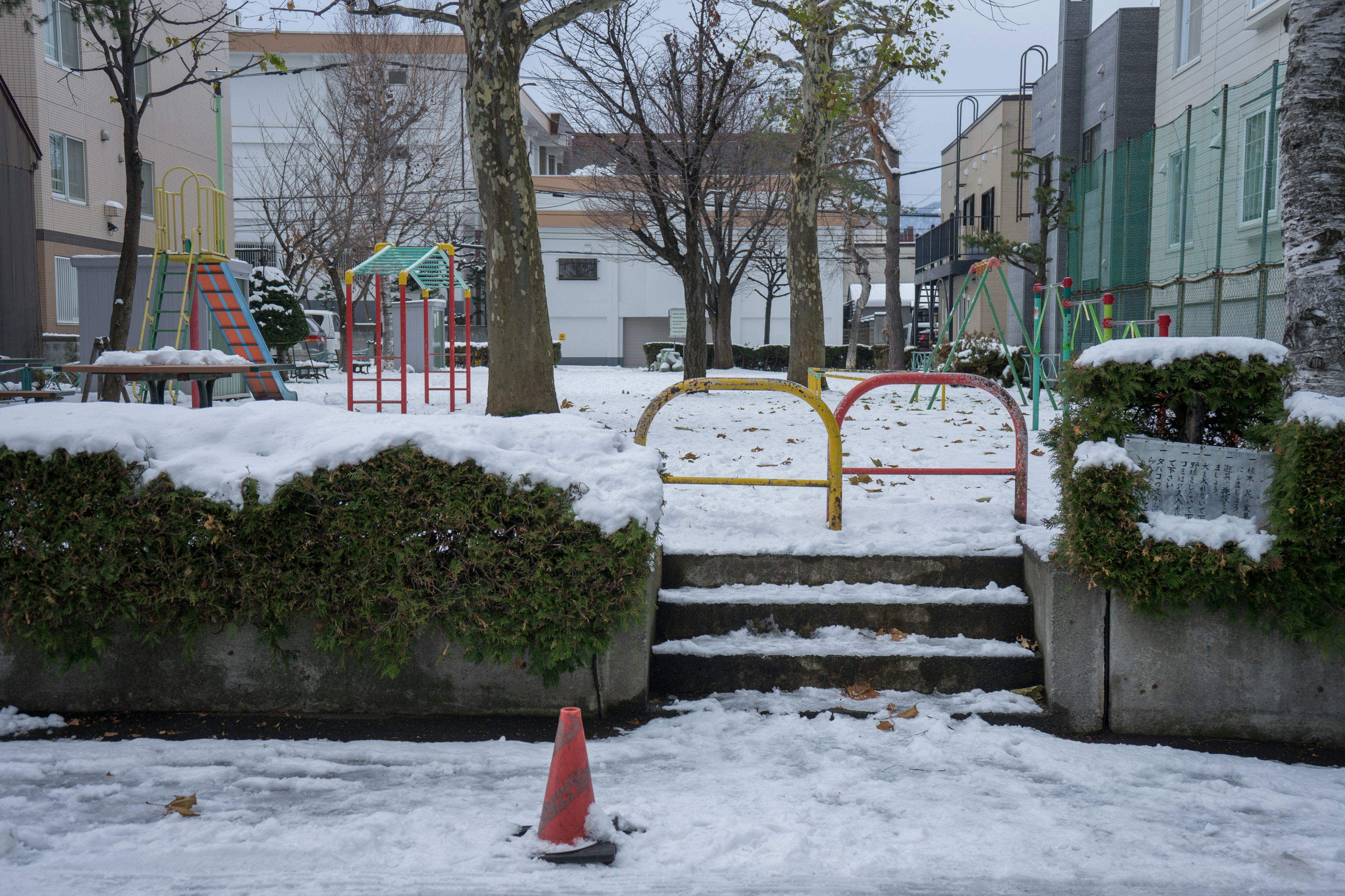 Parque infantil cubierto de nieve con equipos coloridos y escaleras