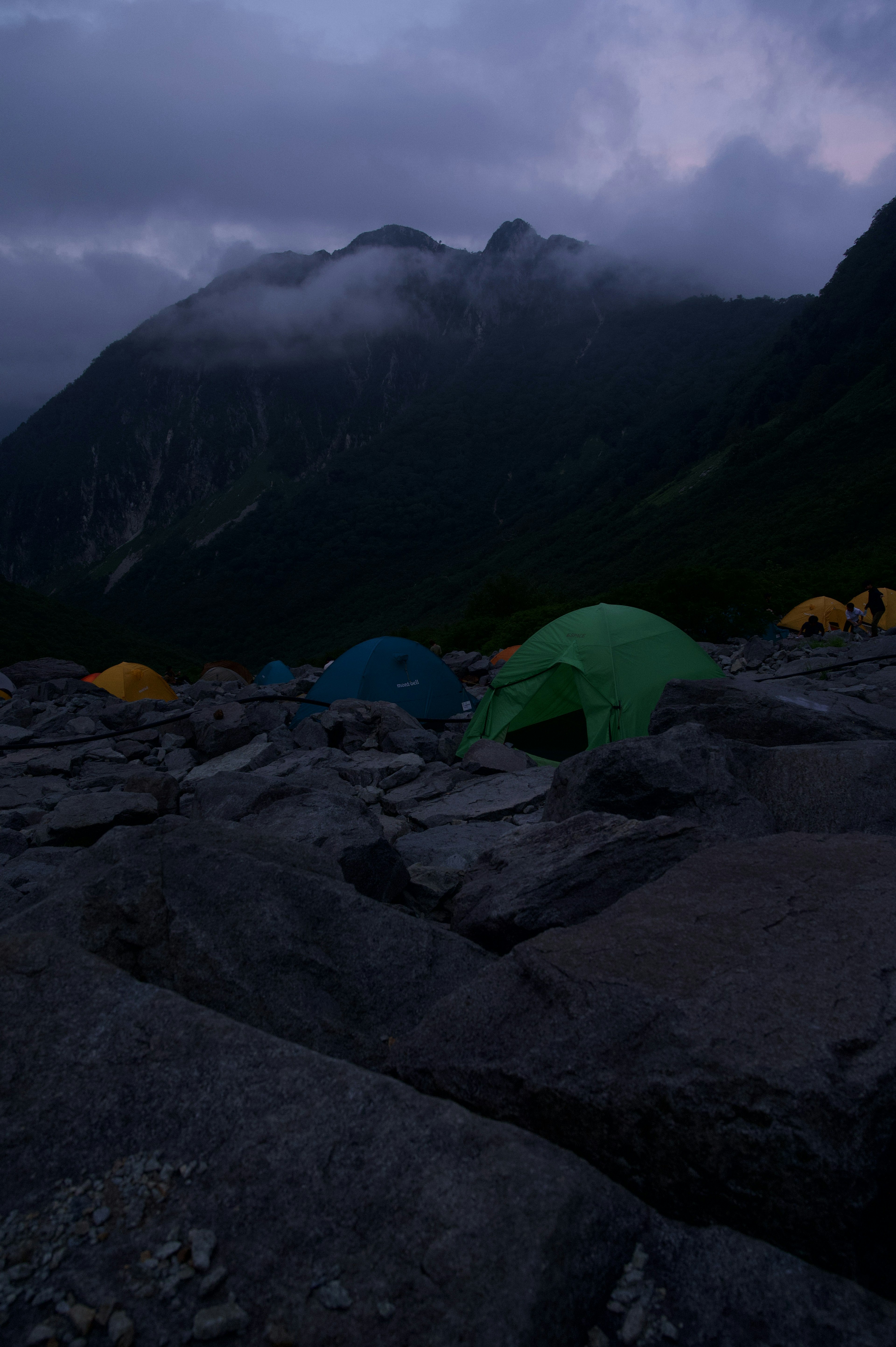 暗い山の風景にテントが点在するキャンプ場