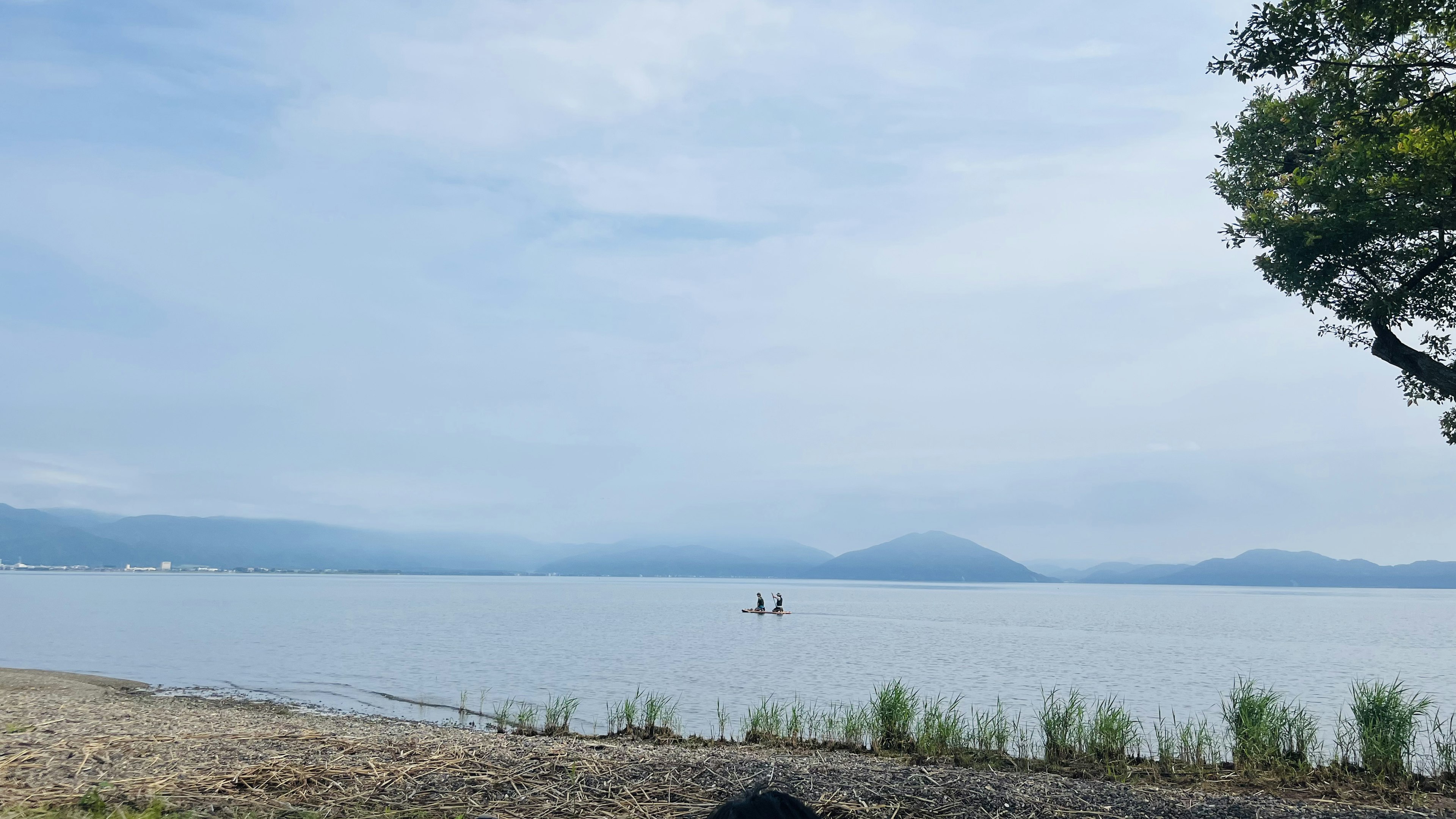 Paesaggio sereno del lago con persone in kayak e montagne in lontananza