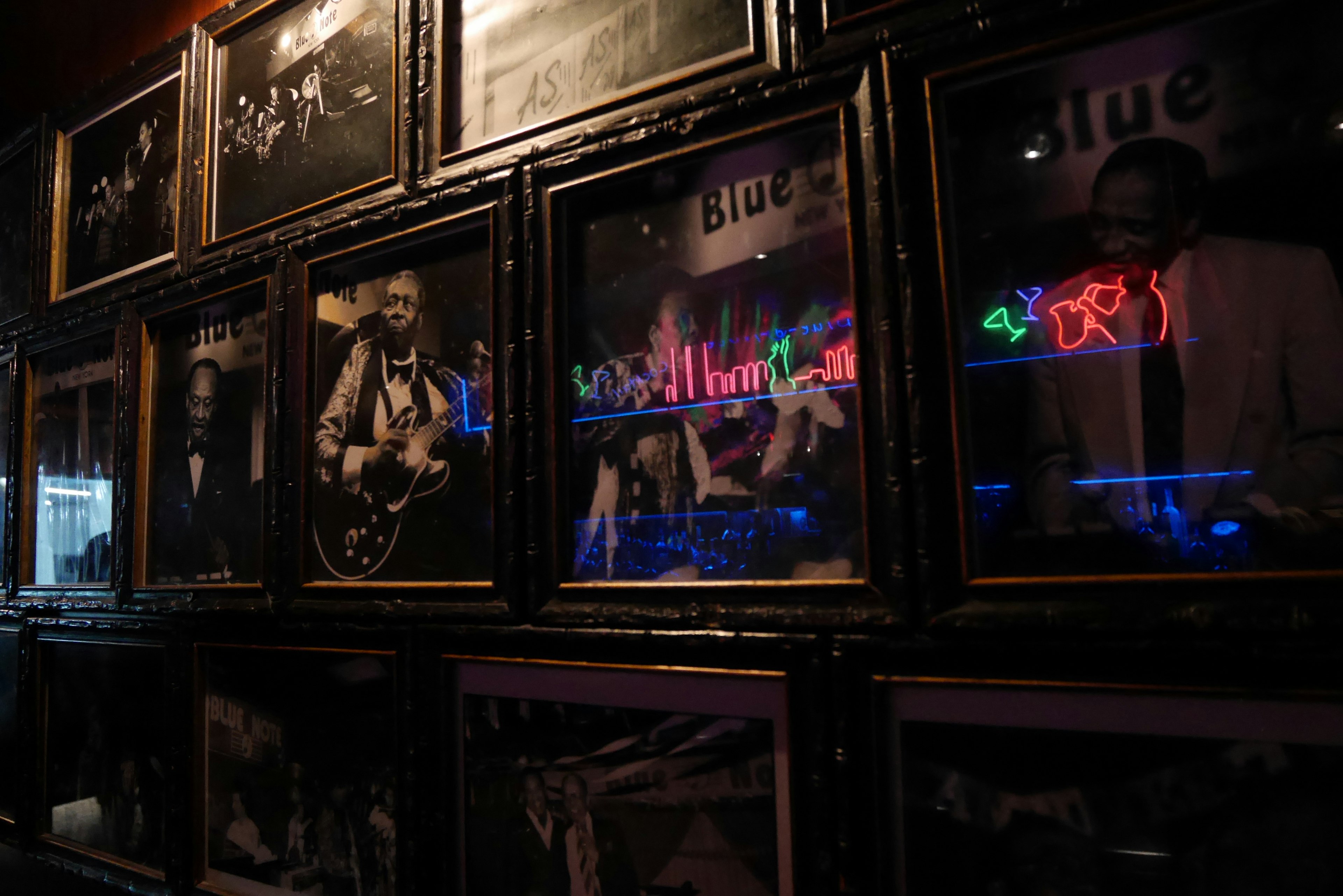 Wall adorned with black and white photographs and blue neon lights