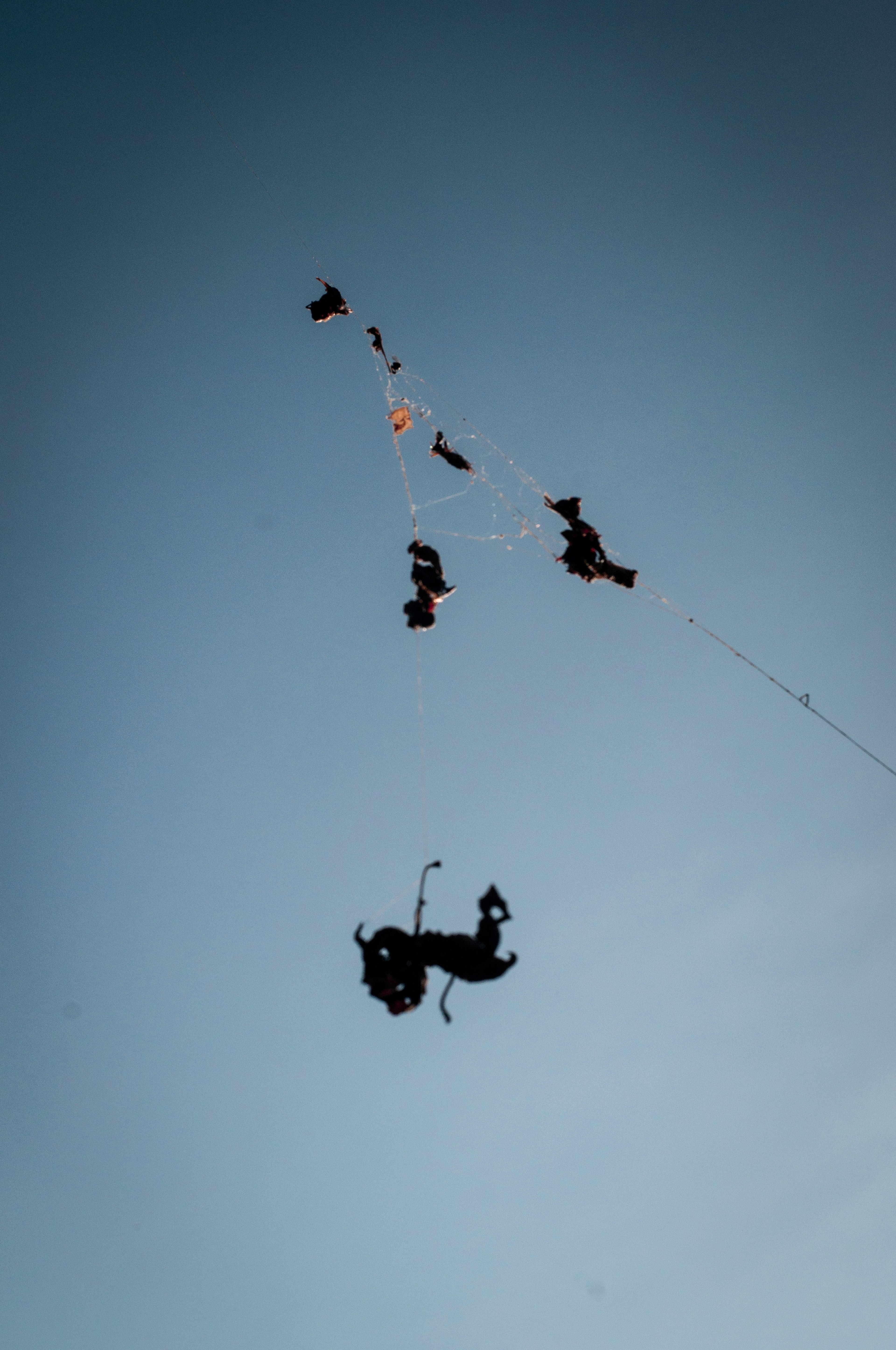 Silhouetten von Drachen und Menschen, die gegen einen klaren blauen Himmel fliegen