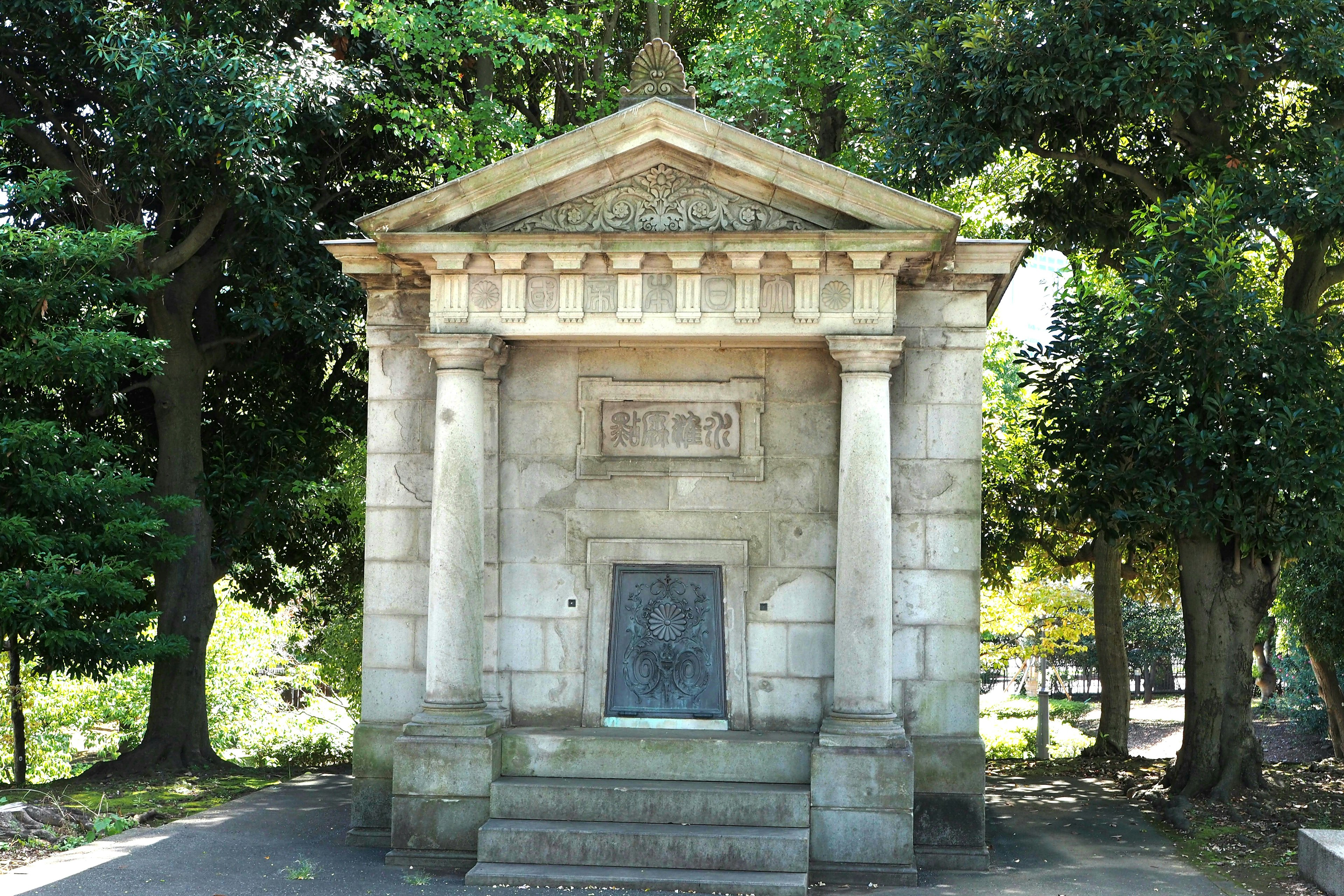 Small stone structure resembling a temple surrounded by greenery in a quiet park