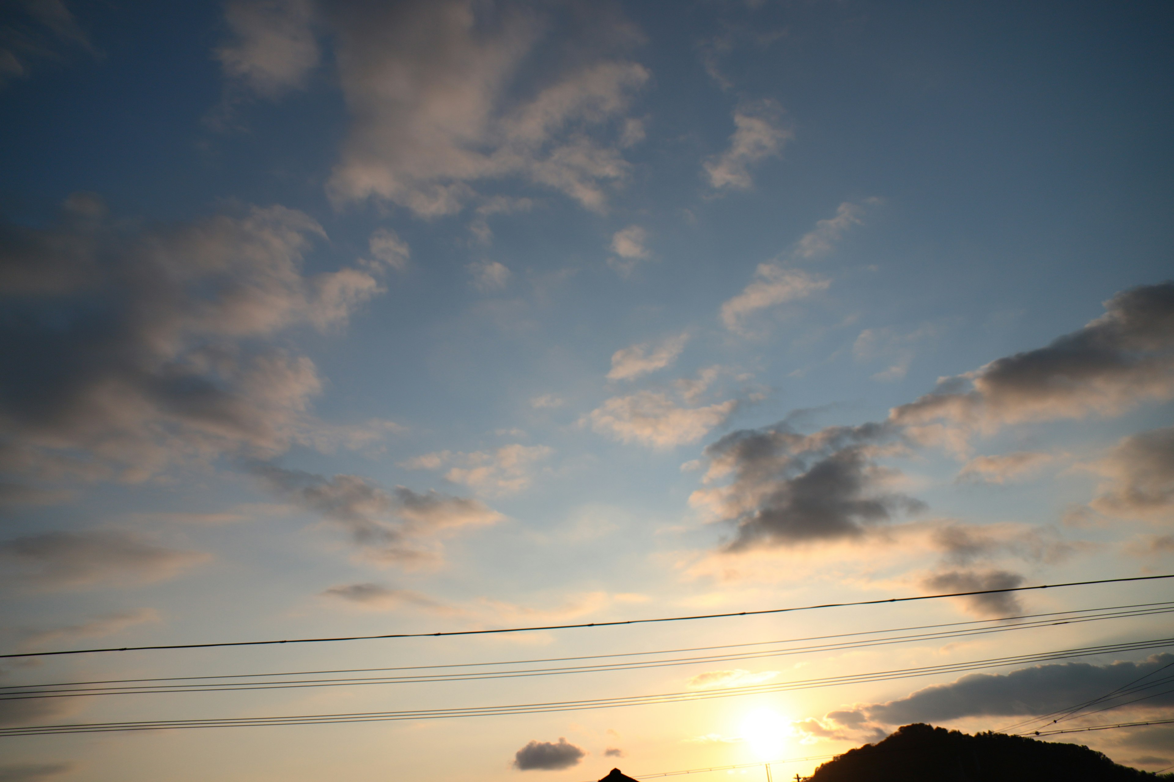 Sonnenuntergangshimmel mit Wolken und Silhouetten von Hügeln