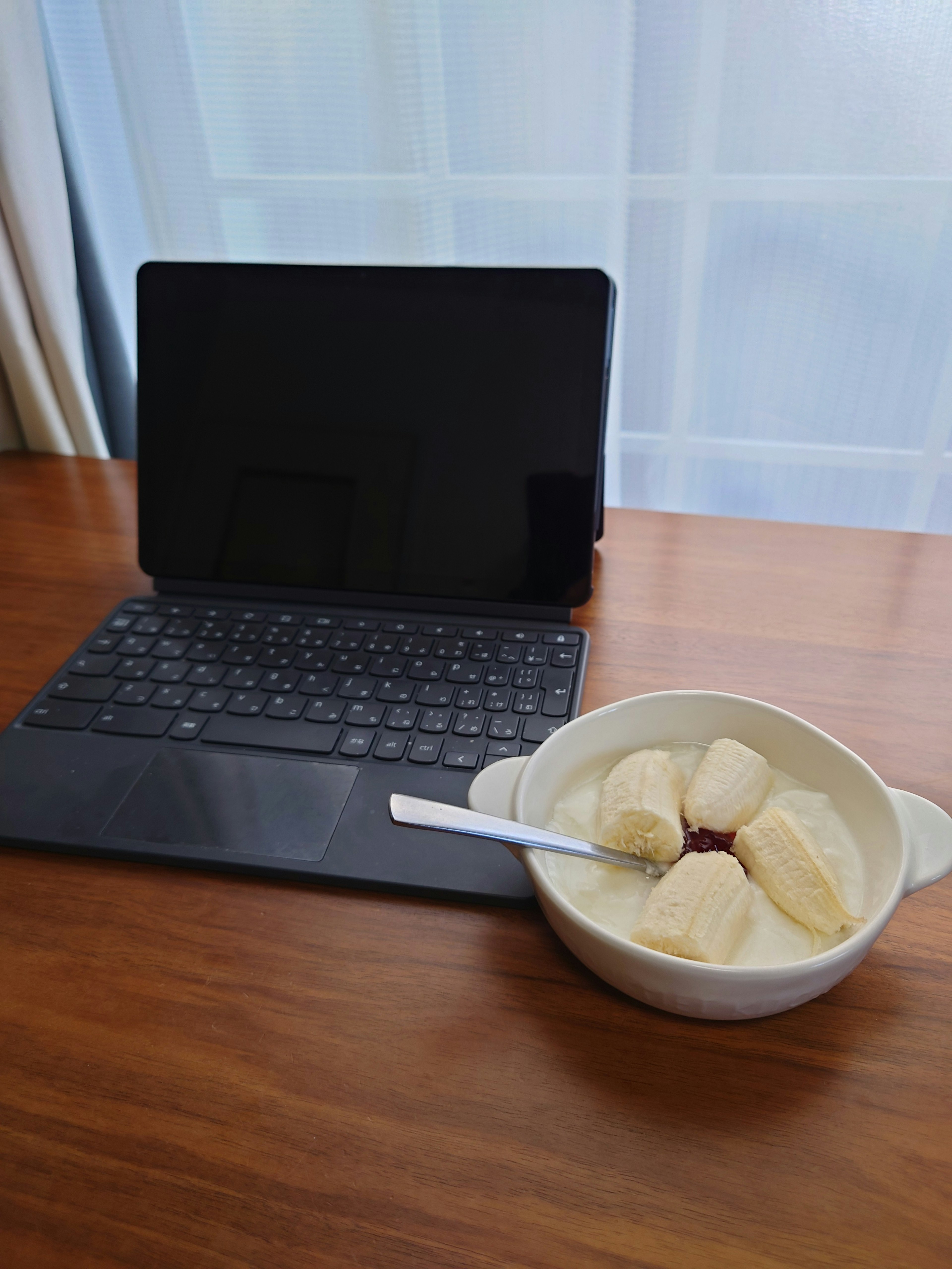 Tablet on a wooden table next to a bowl of ice cream