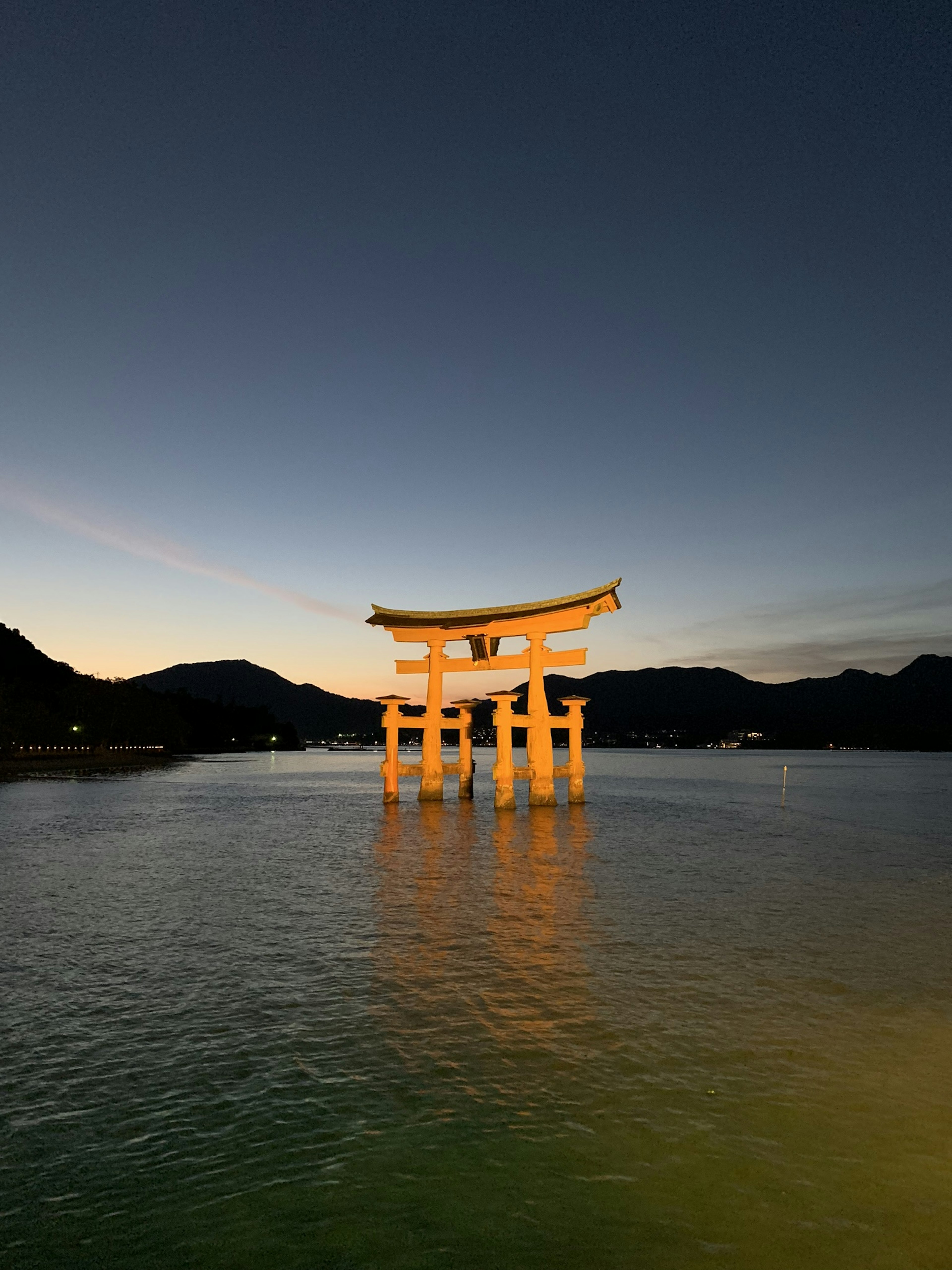 El torii del santuario de Itsukushima flotando en el mar al anochecer