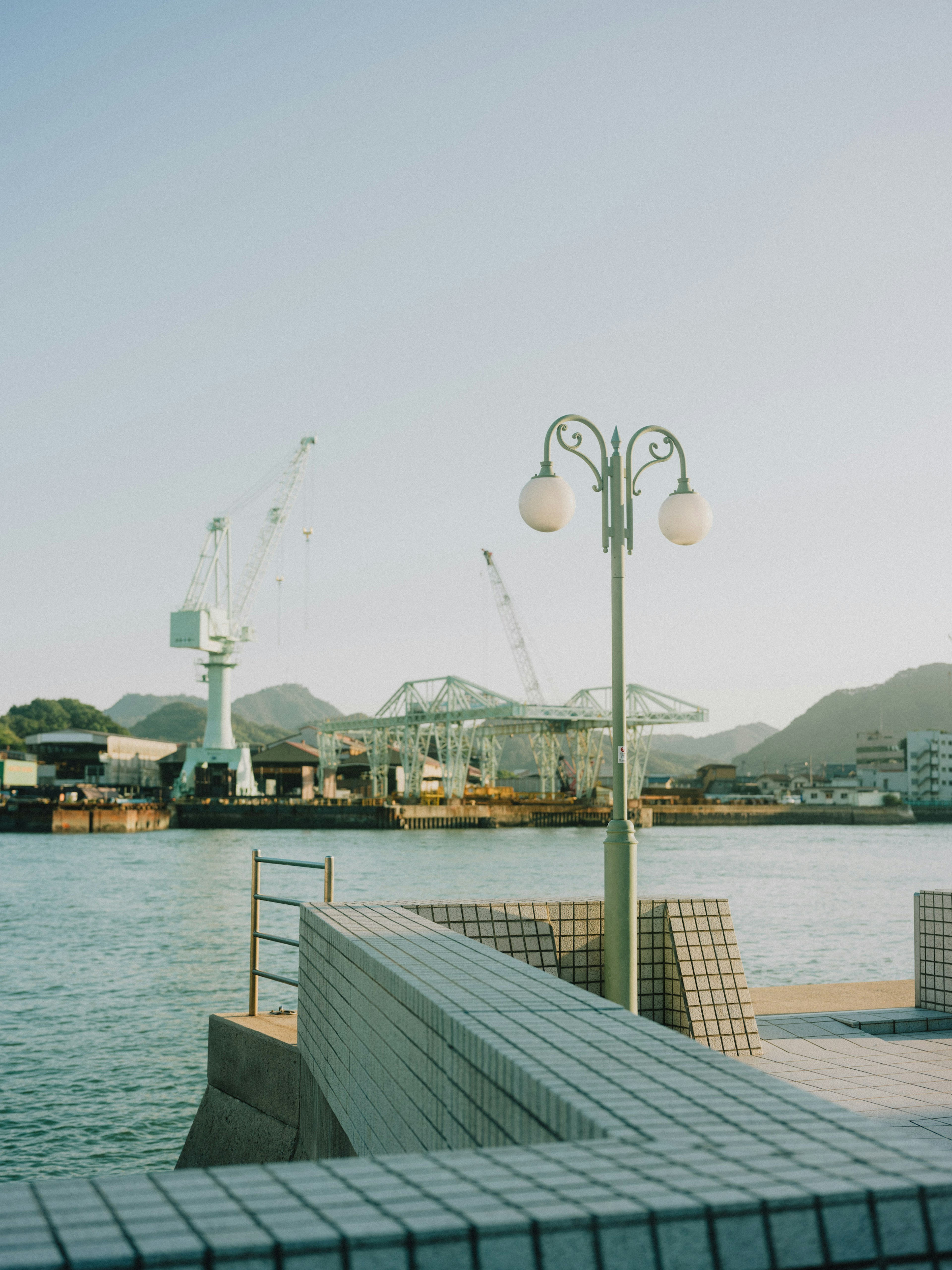 Quiet harbor scene featuring a lamppost and cranes