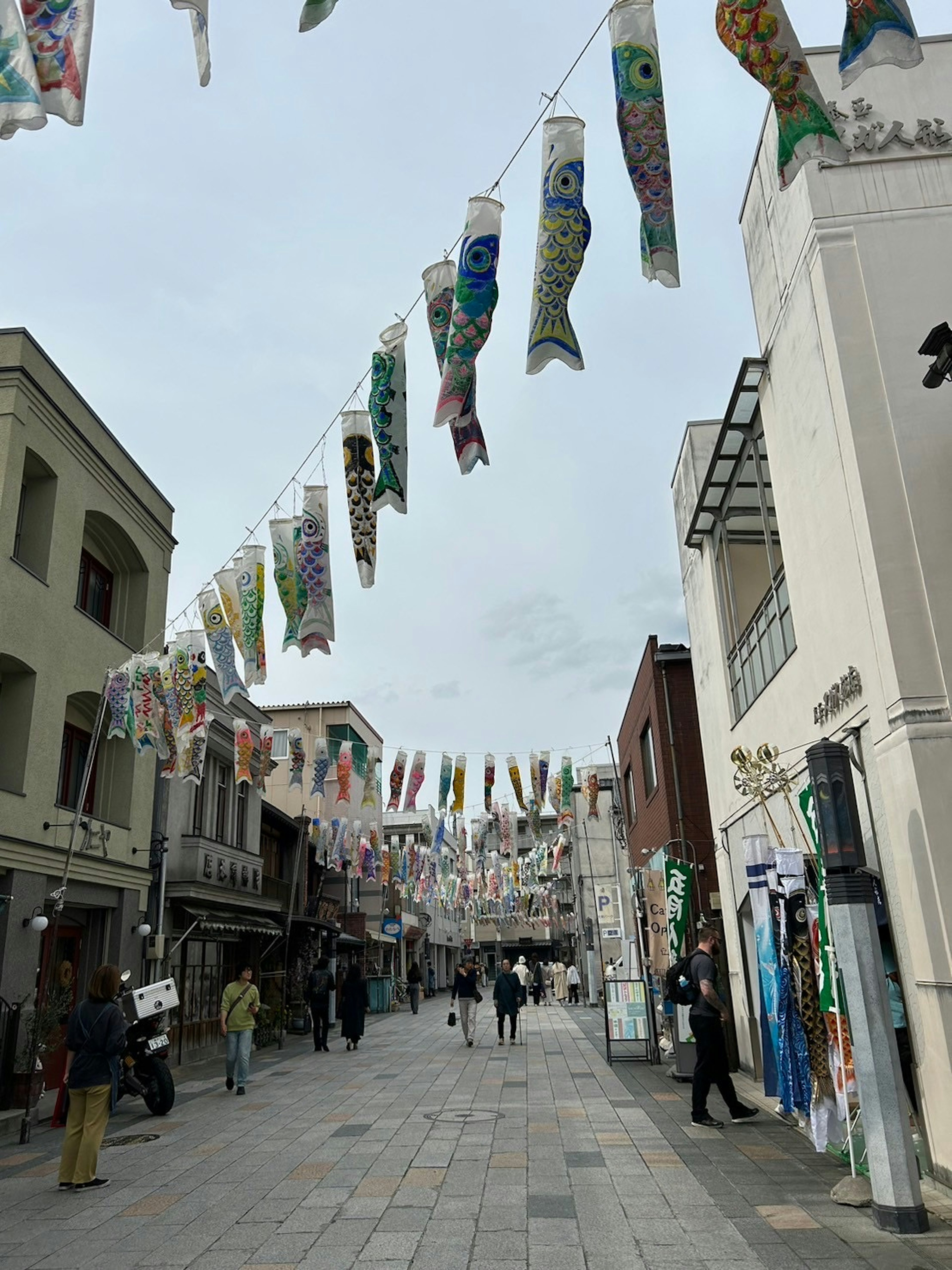 Décorations colorées de koinobori suspendues au-dessus d'une rue animée avec des gens qui marchent