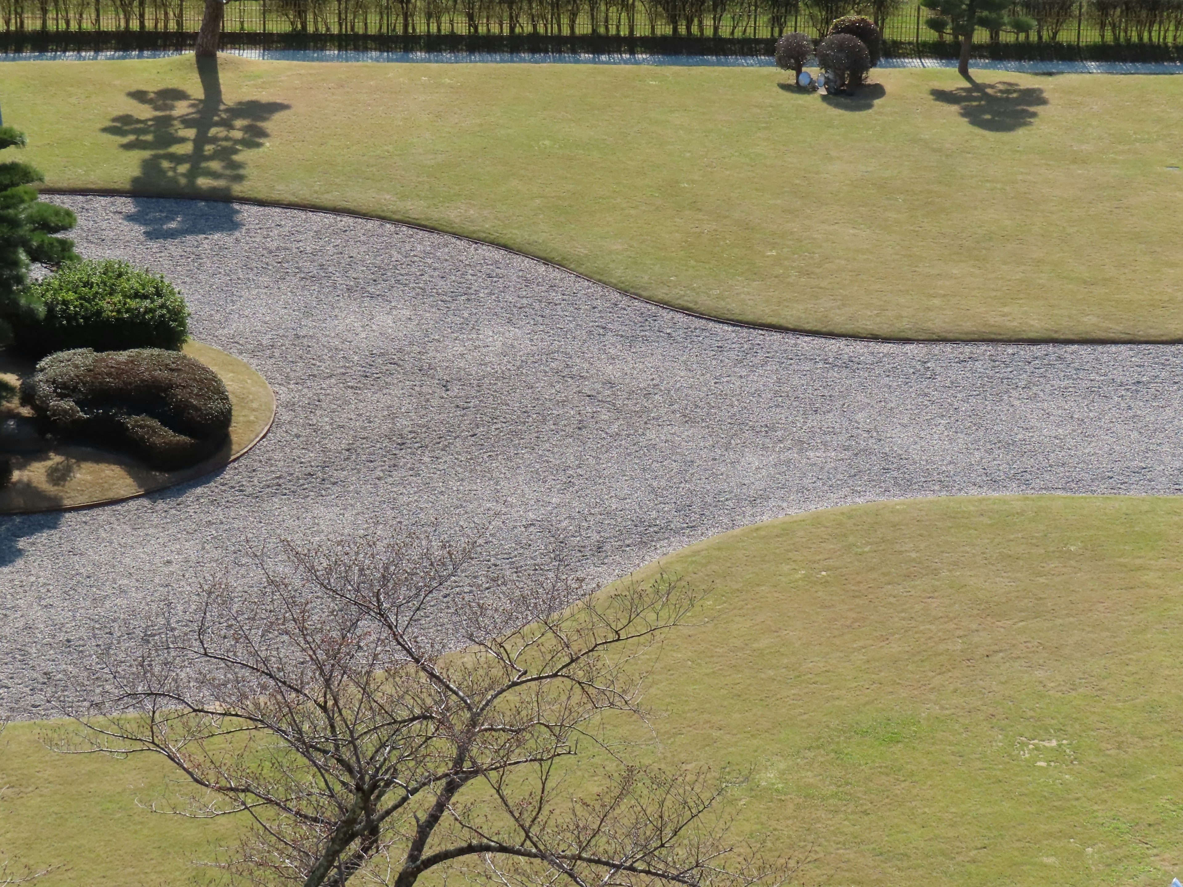 美しい庭の風景、曲がりくねった小道、石、緑の芝生、木々が見える