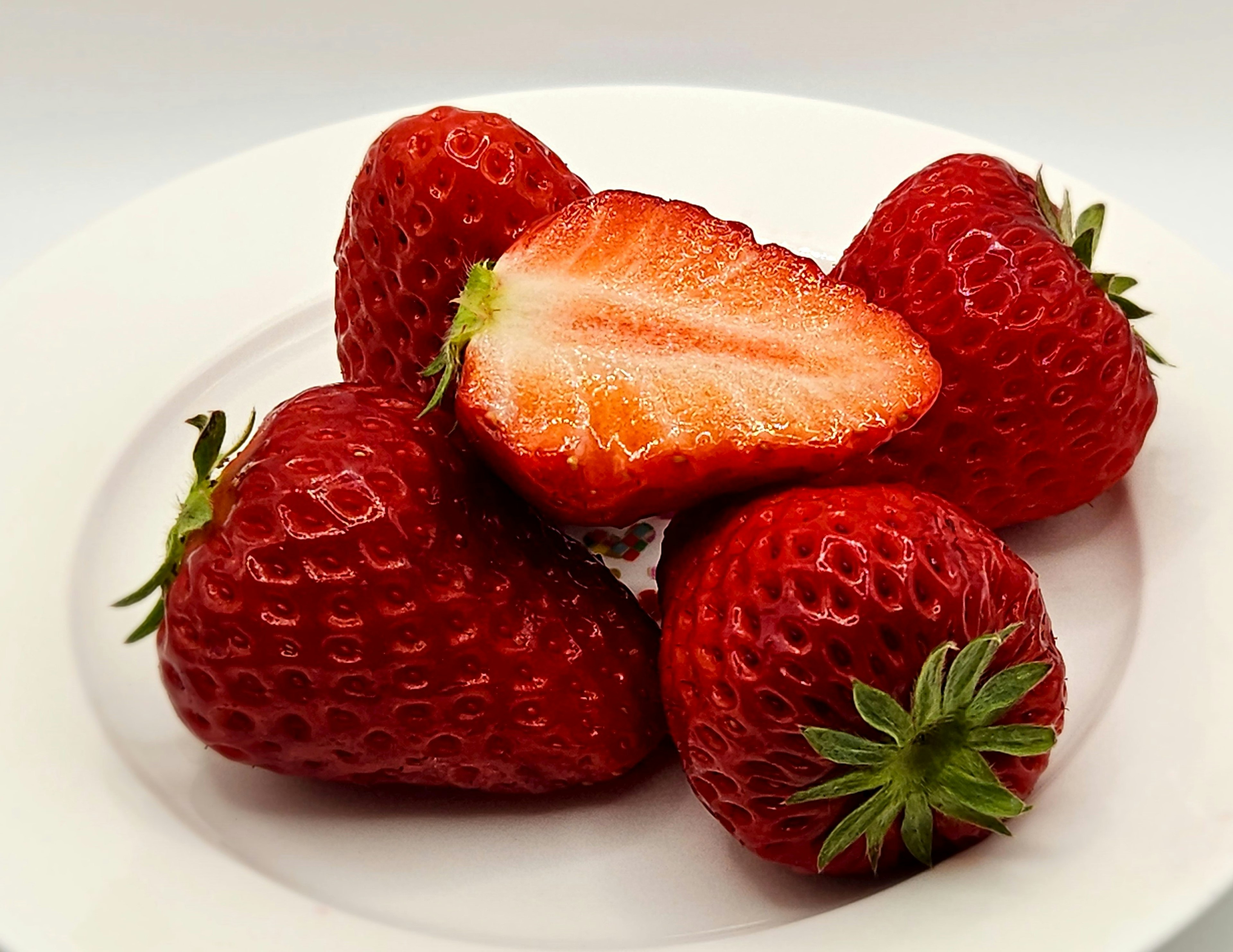 Una colección de fresas frescas en un plato blanco