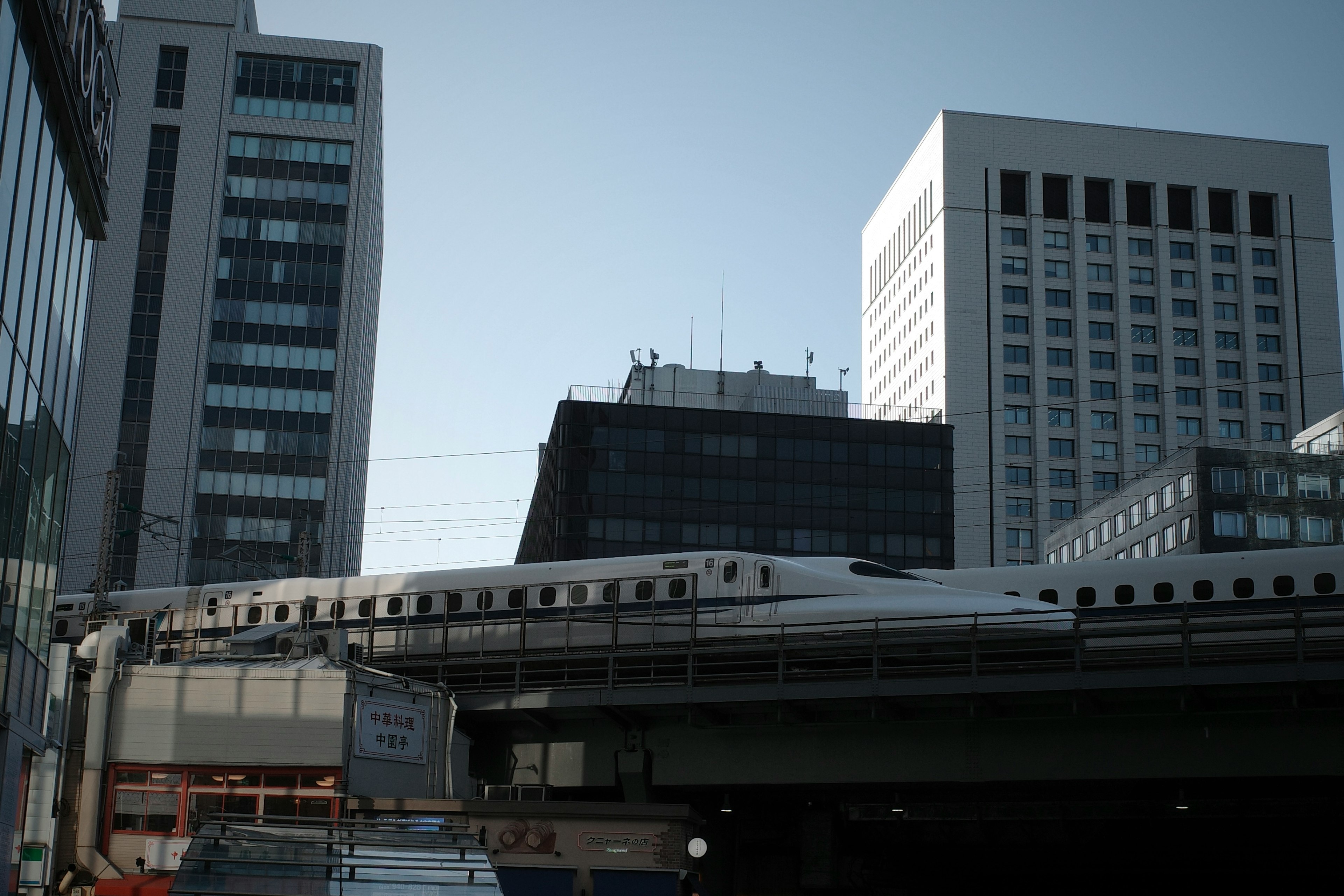 Shinkansen train traveling through a cityscape with tall buildings