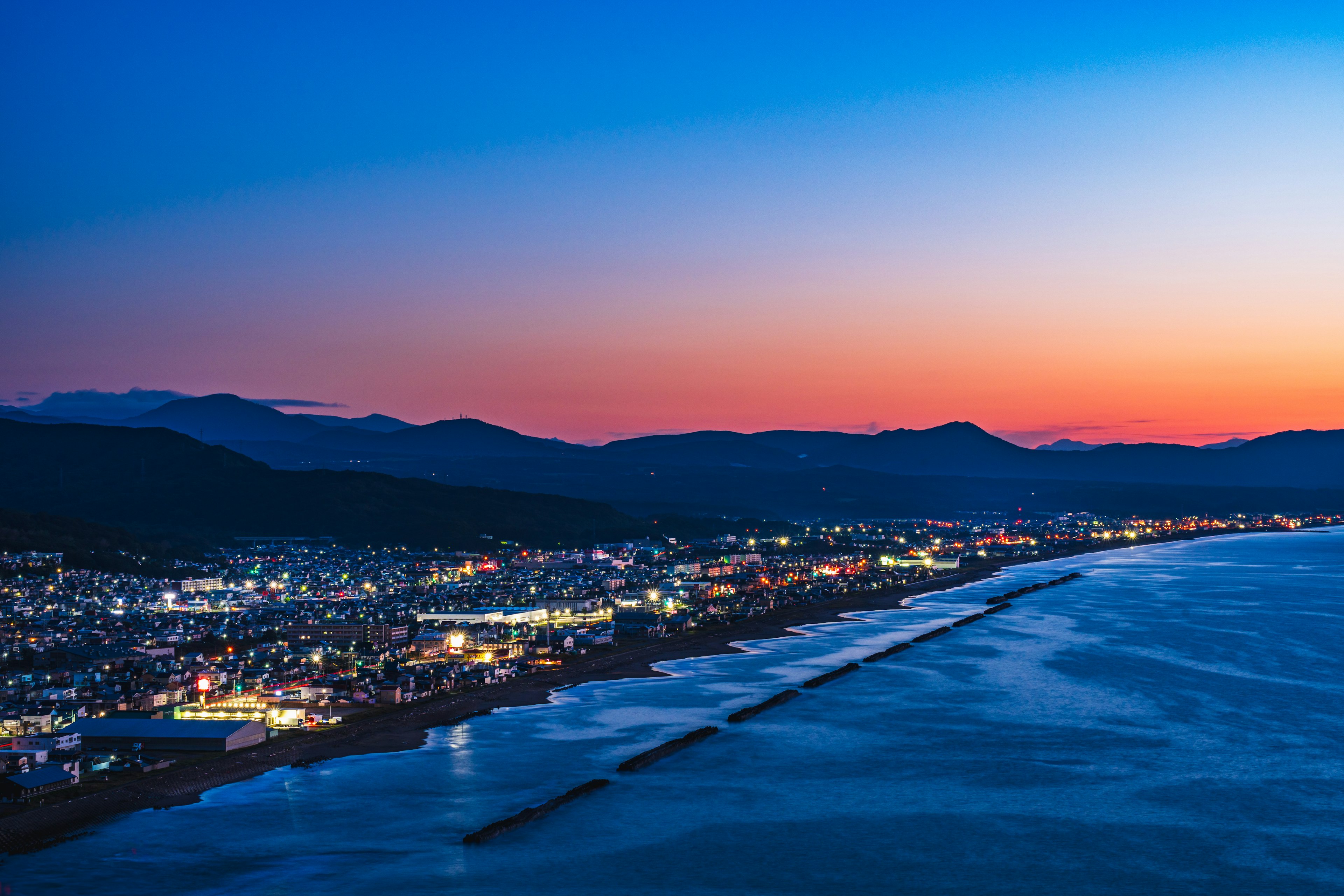 夕暮れの海岸線と都市の夜景