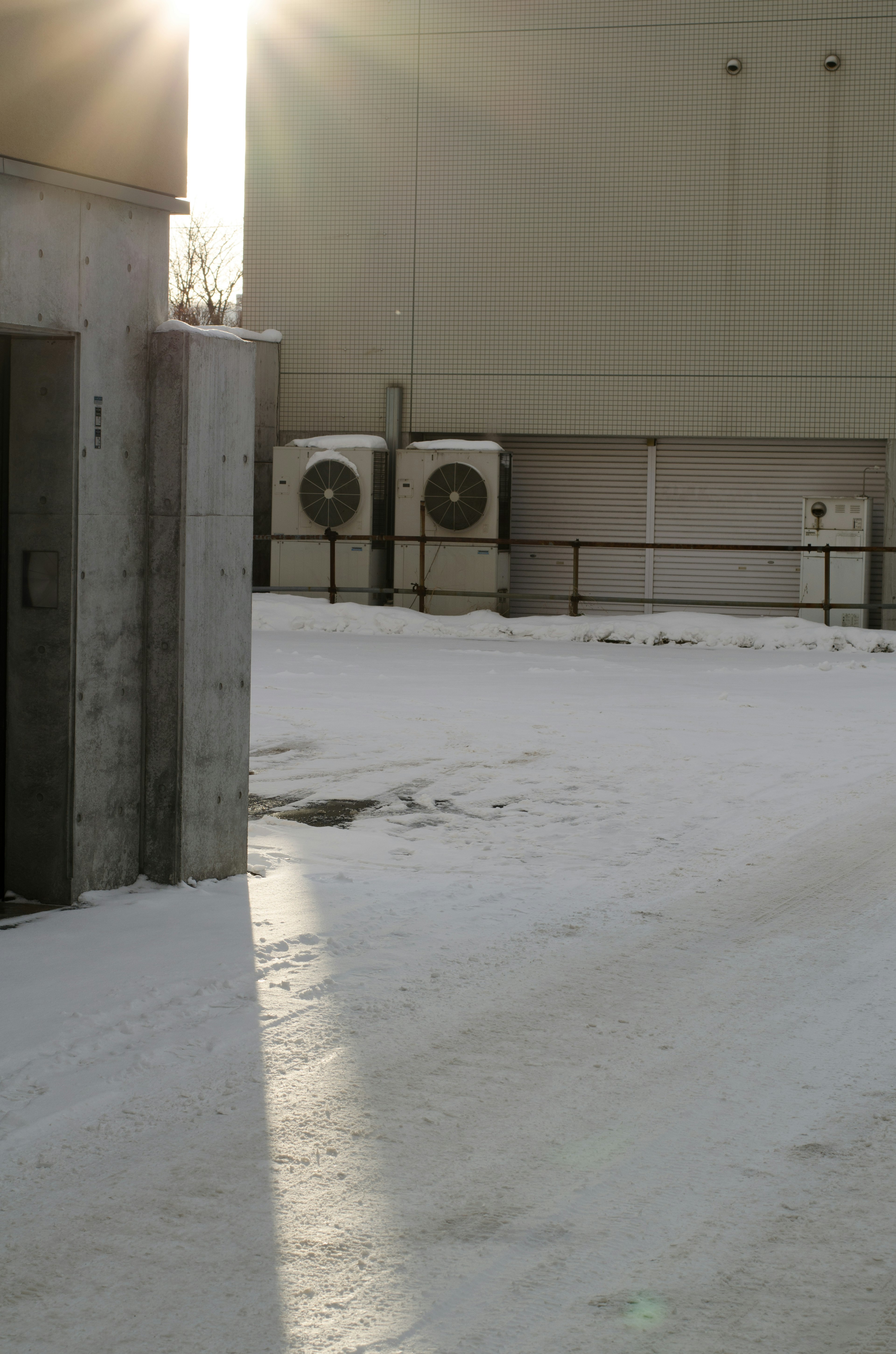 Exterior view of a building with snow-covered ground and air conditioning units