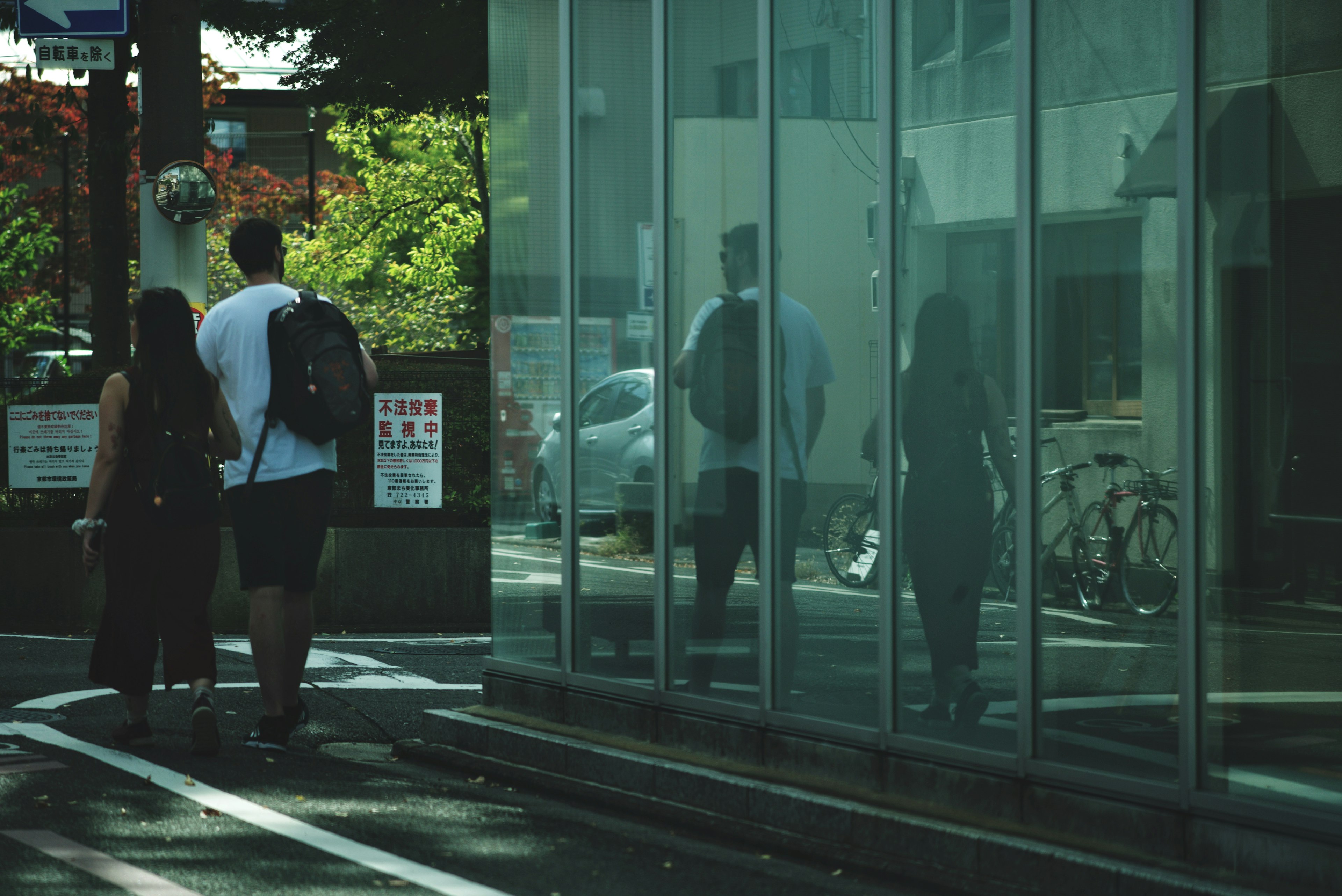 People walking by a glass building with reflections of the street