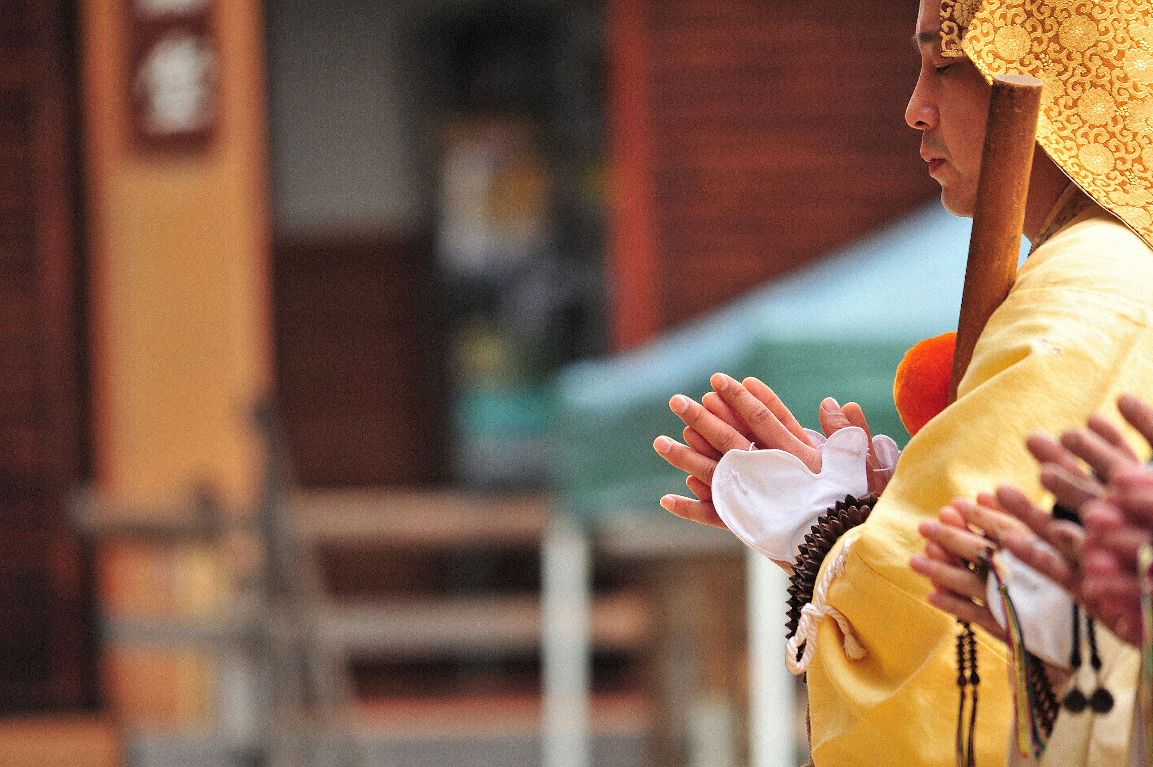 Woman in yellow attire with hands clasped in prayer