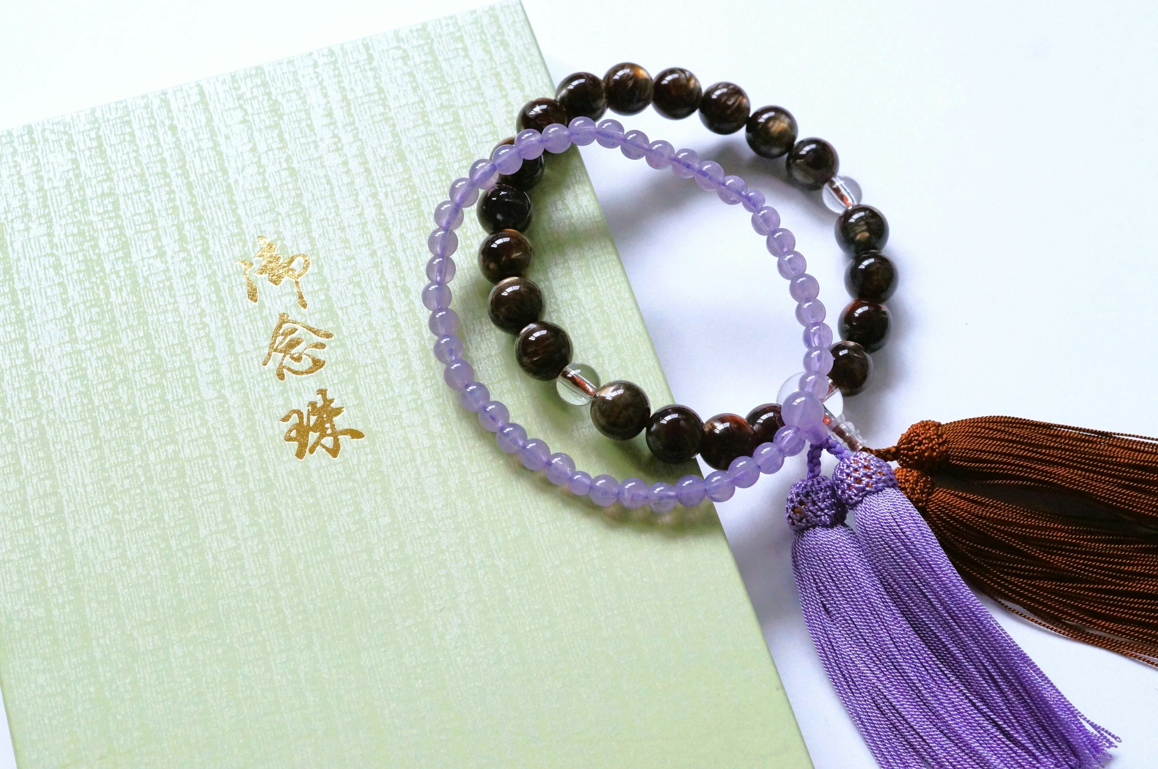 Bracelets de prière avec des glands violet et marron posés sur une enveloppe verte