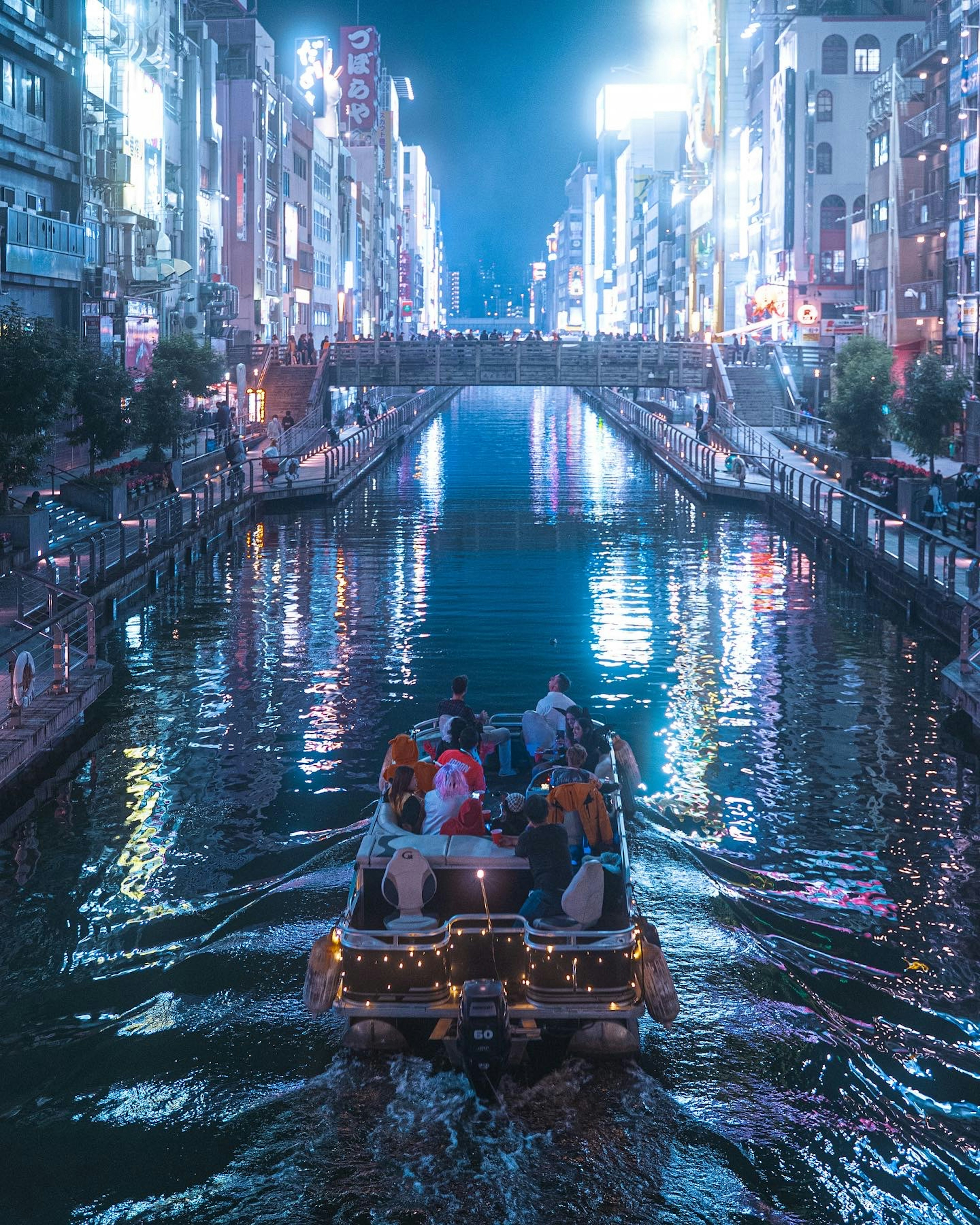 Bateau naviguant dans un canal sous des lumières néon brillantes la nuit