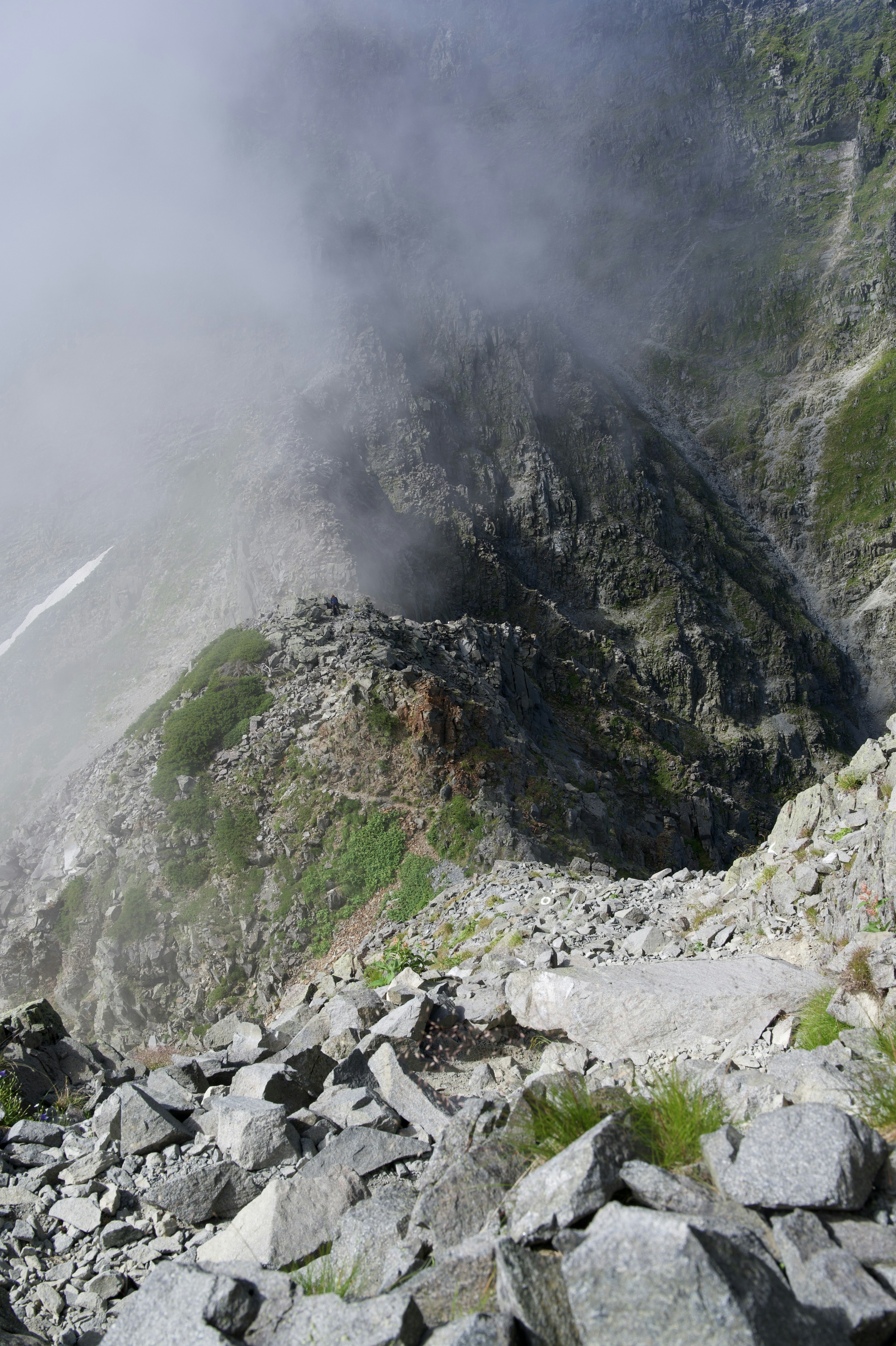 Mountain slope shrouded in mist with rocky terrain