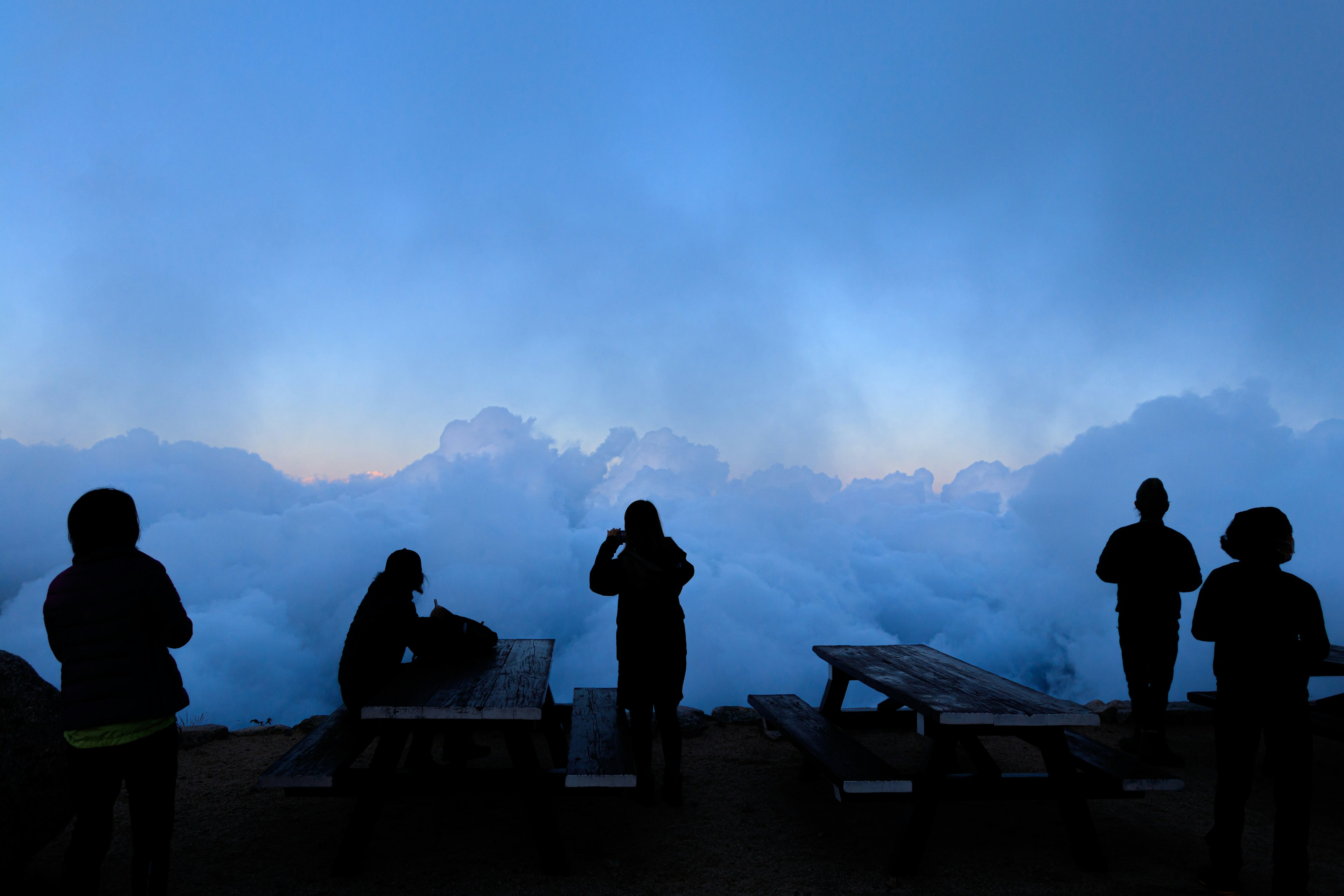 Silhouetten von Menschen vor einem blauen Himmel und Wolken