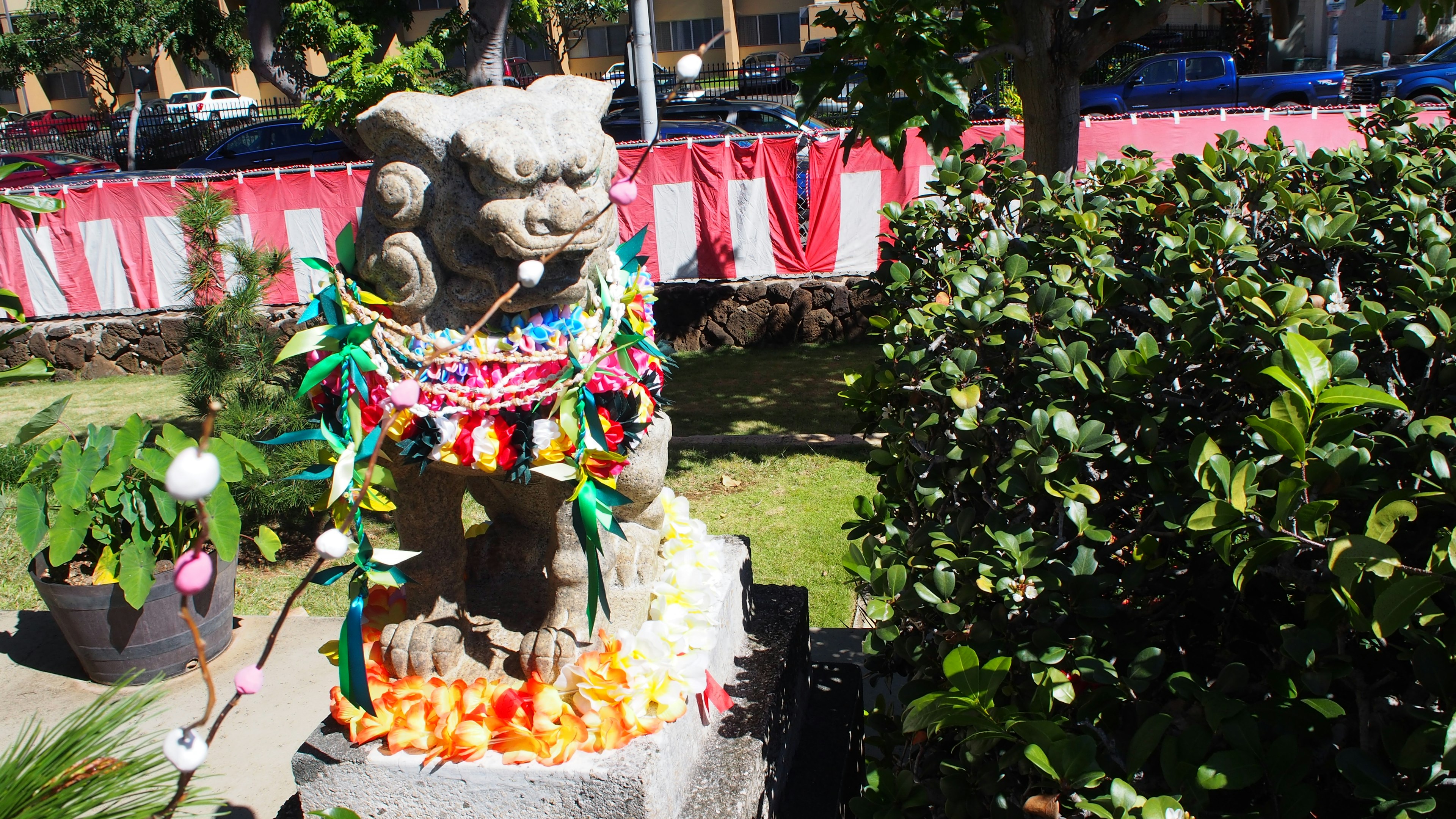 Une statue de lion en pierre ornée de décorations florales dans un jardin