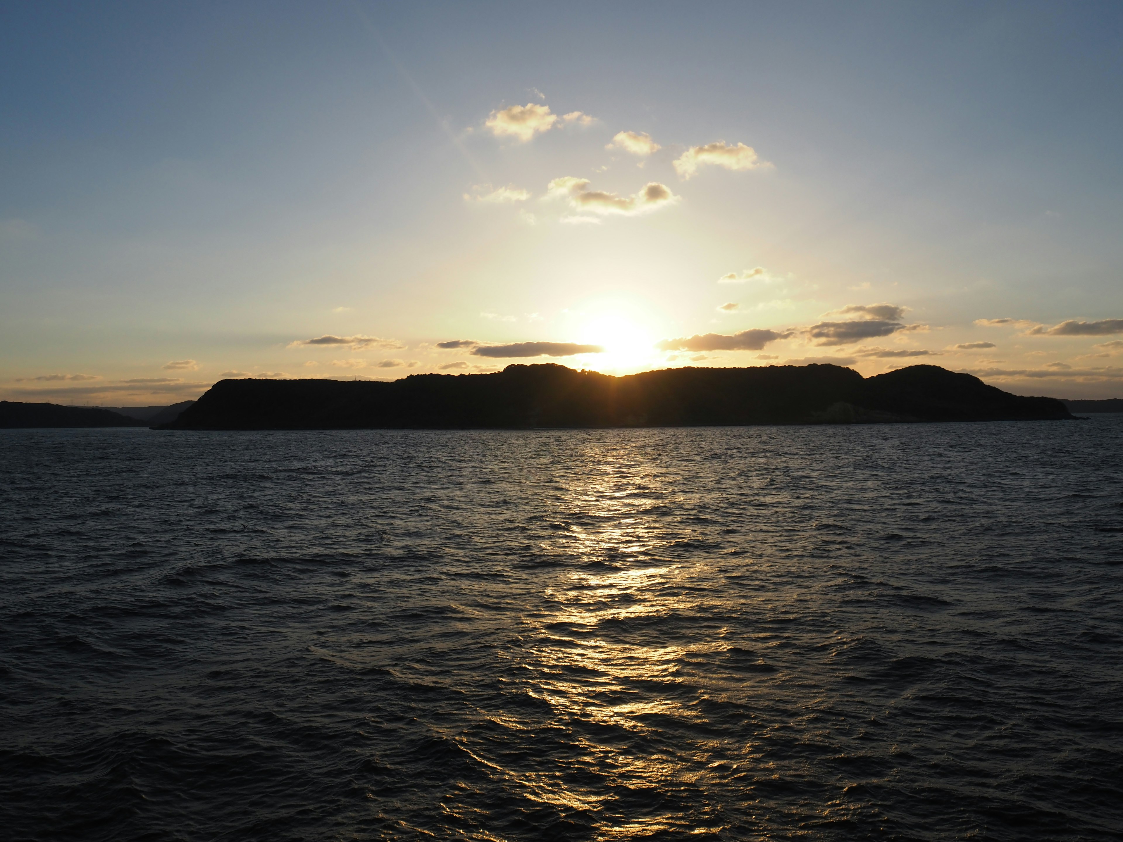 Sunset over the ocean with silhouetted hills