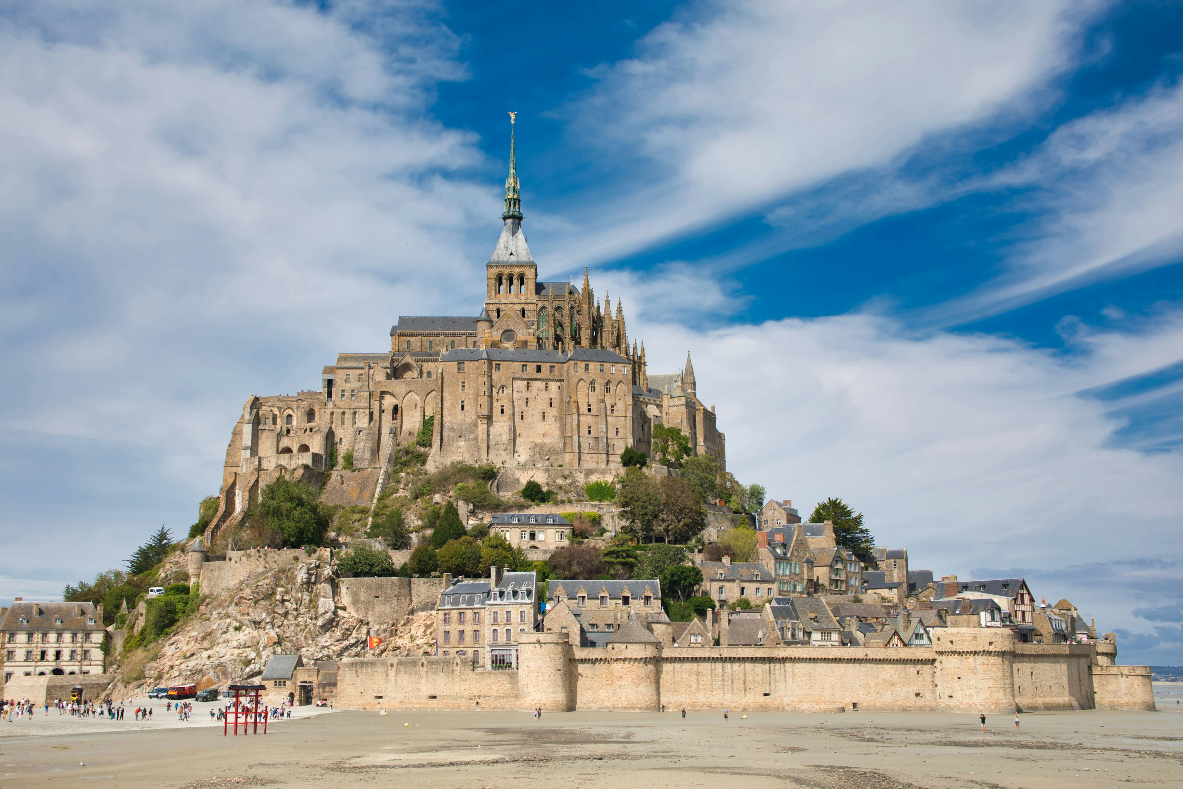 Mont Saint-Michel con un cielo drammatico e un primo piano sabbioso