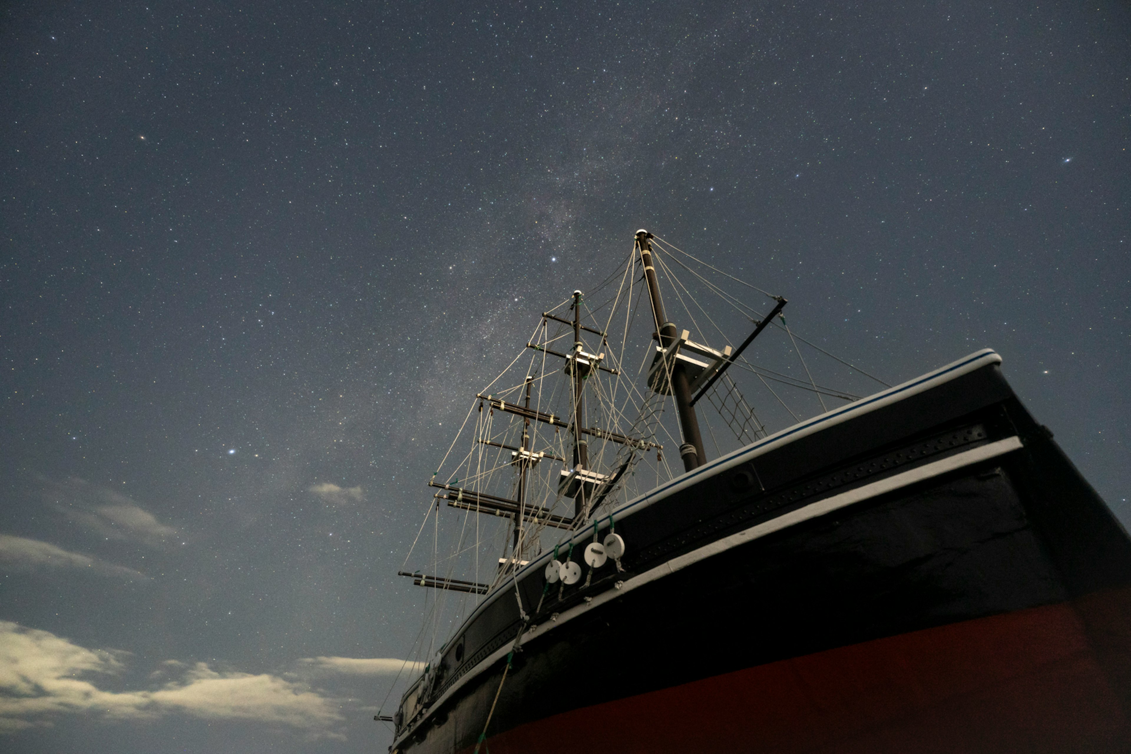 Primo piano di una vecchia nave a vela sotto un cielo stellato con scafo nero e rosso