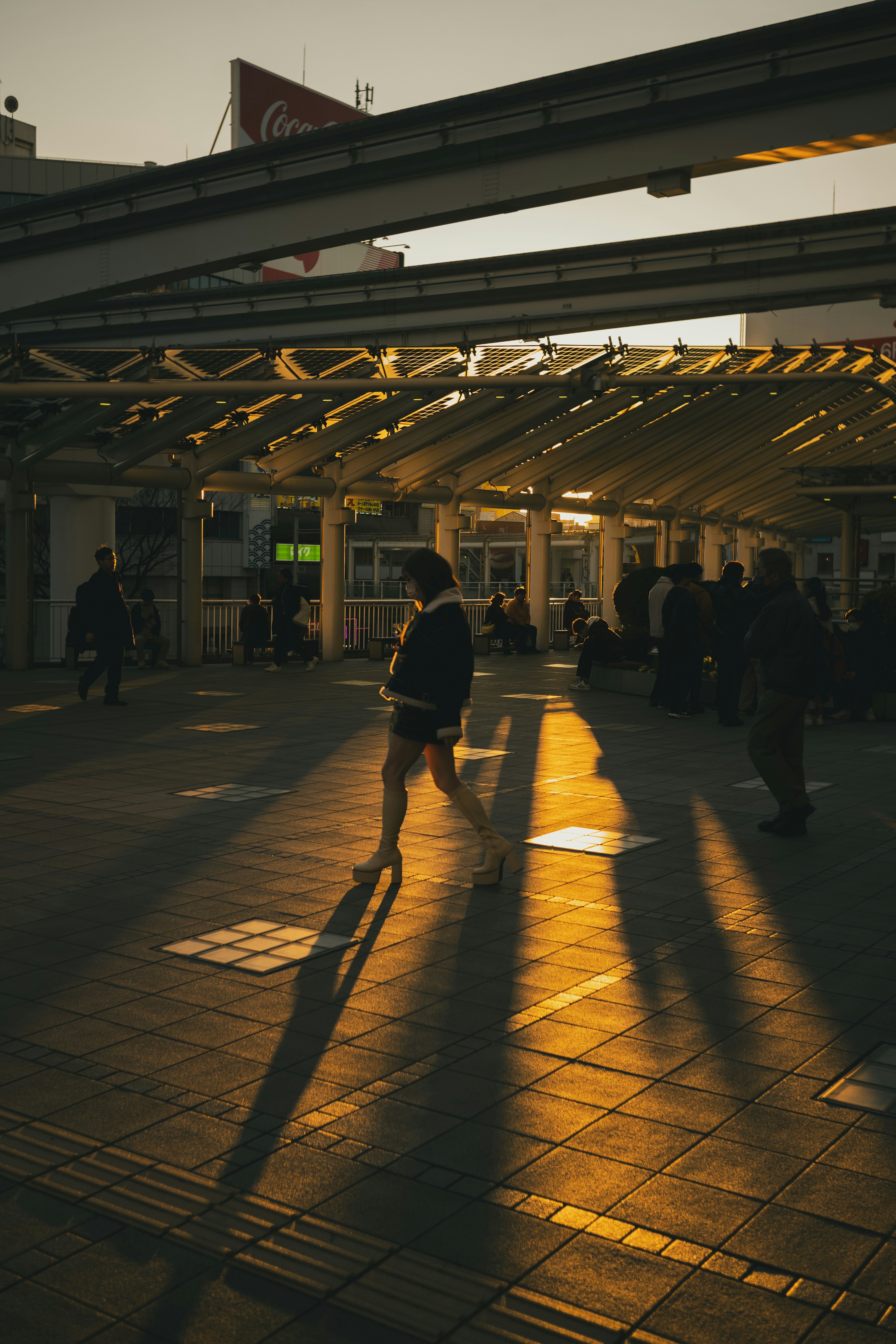 Eine Szene an einem Bahnhof bei Sonnenuntergang mit Menschen, die gehen und langen Schatten