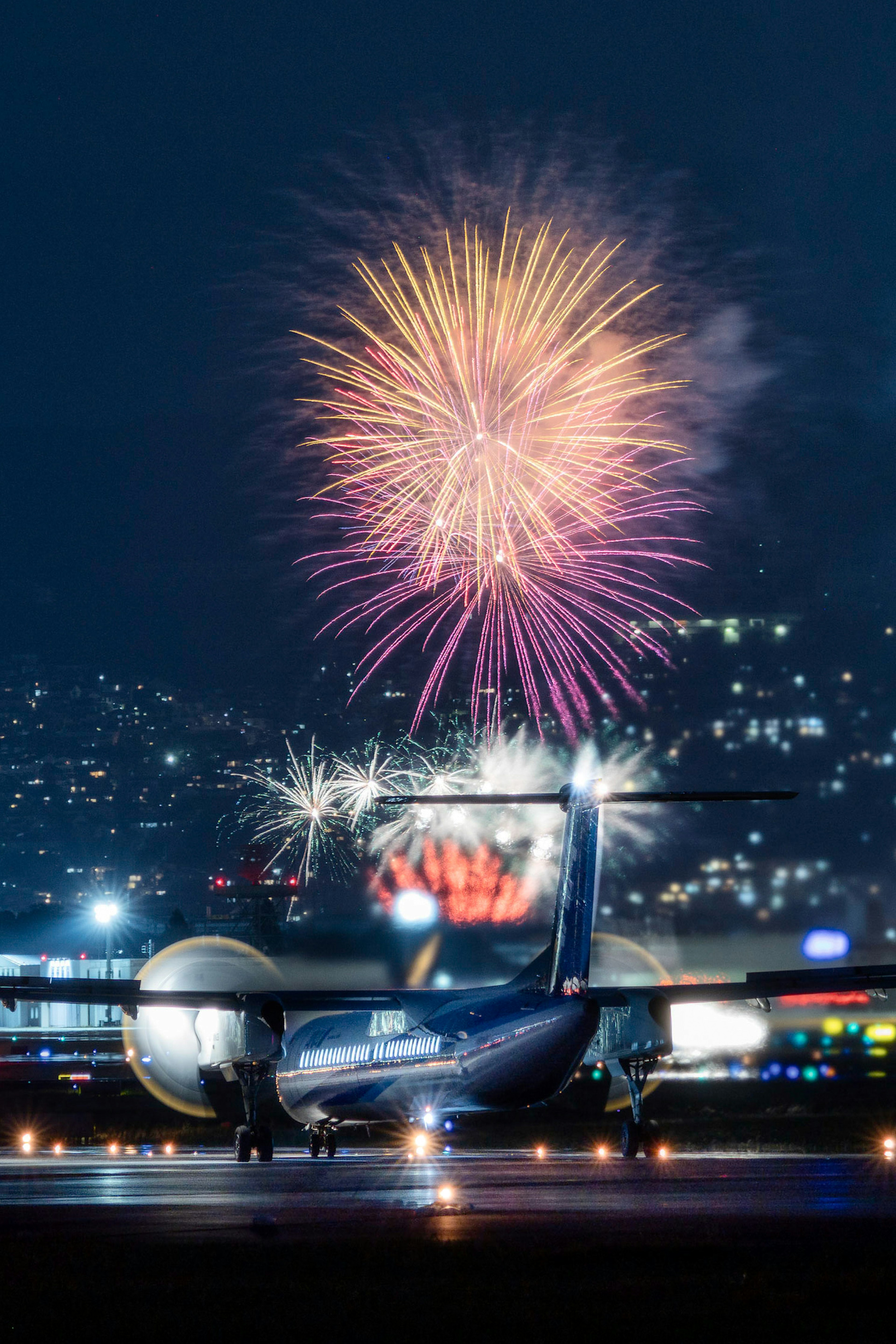 夜空中綻放煙火的機場跑道上的飛機