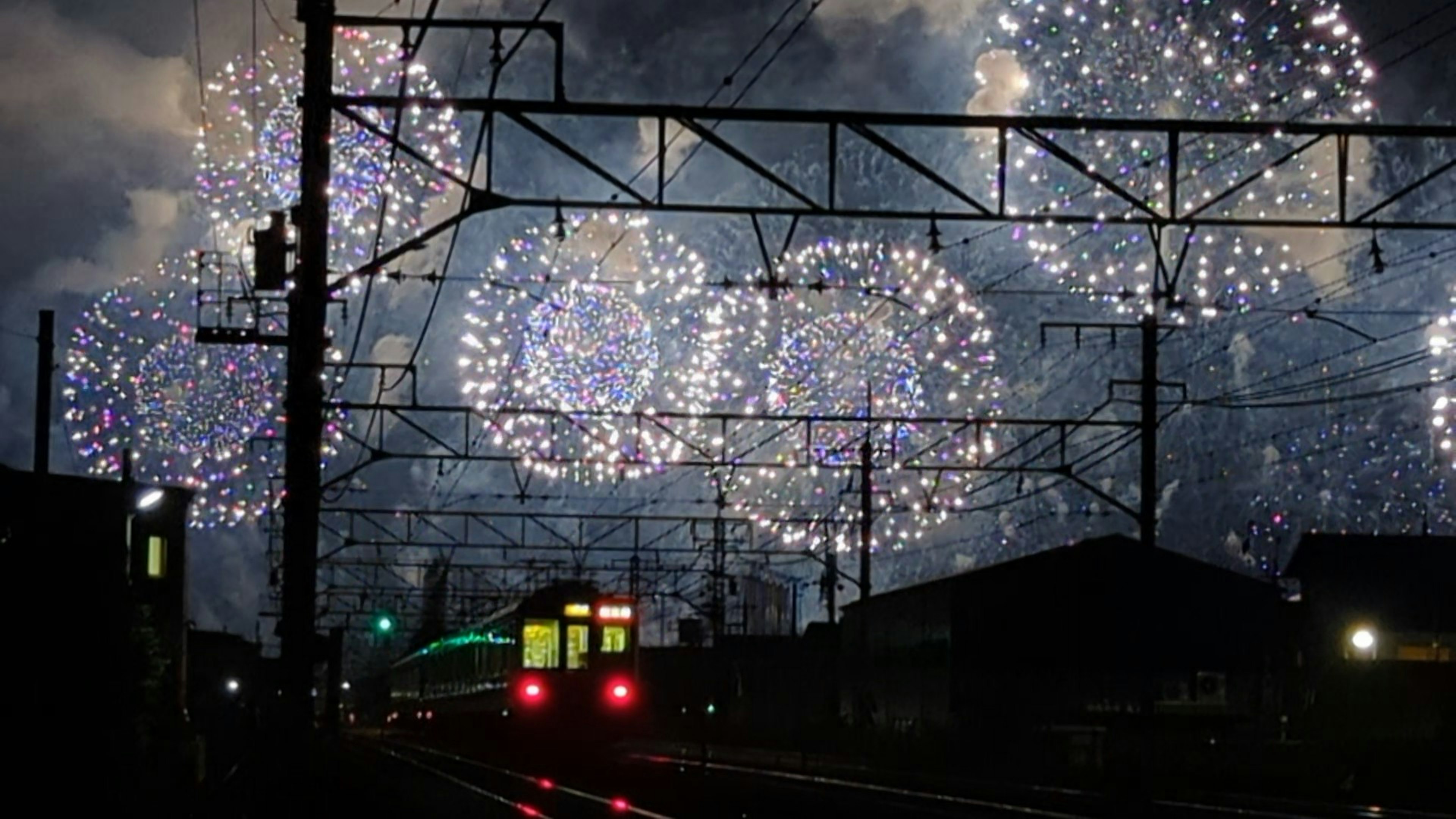 夜空に広がる花火と鉄道のシルエット