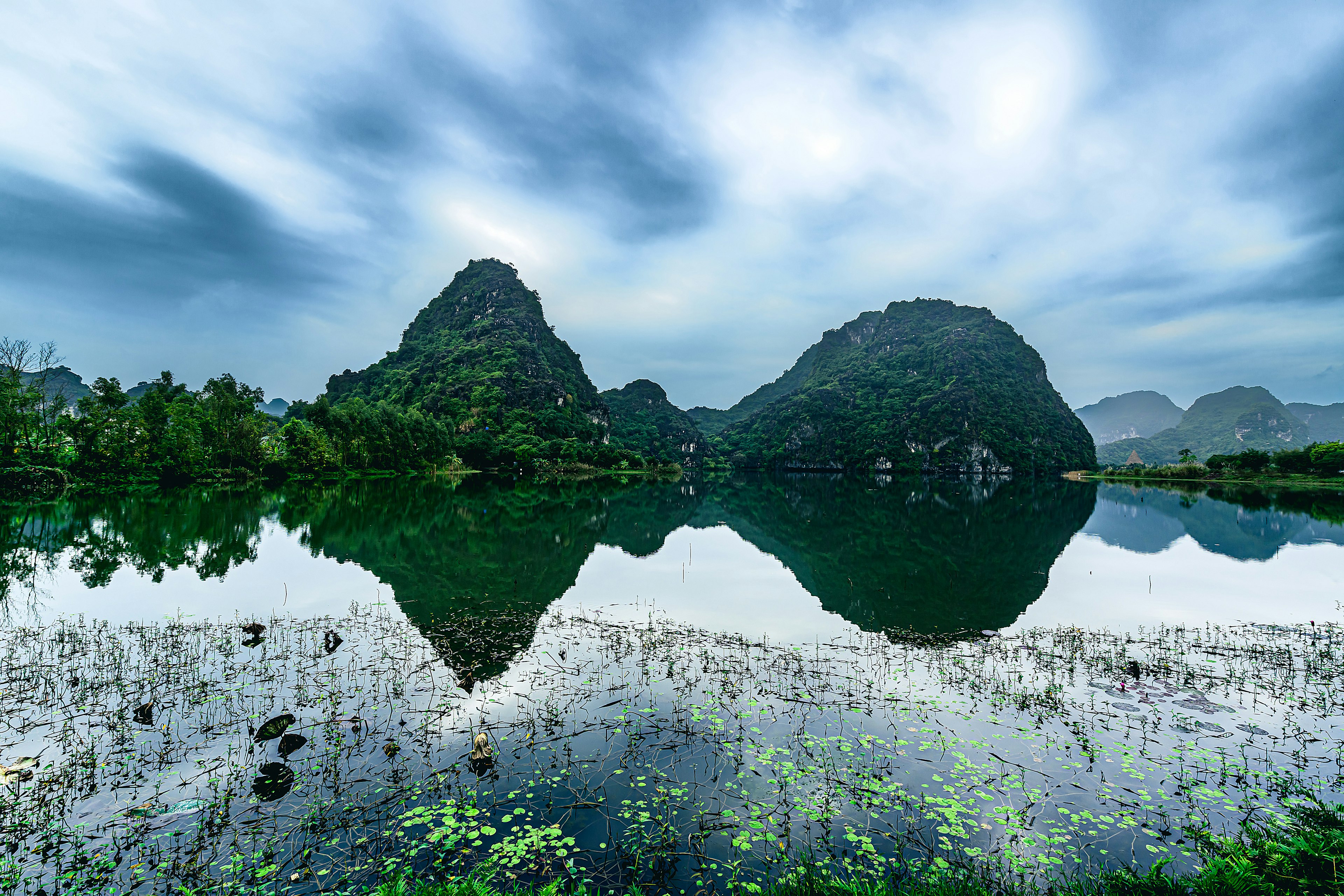 Vista escénica de montañas reflejándose en un lago tranquilo bajo un cielo azul