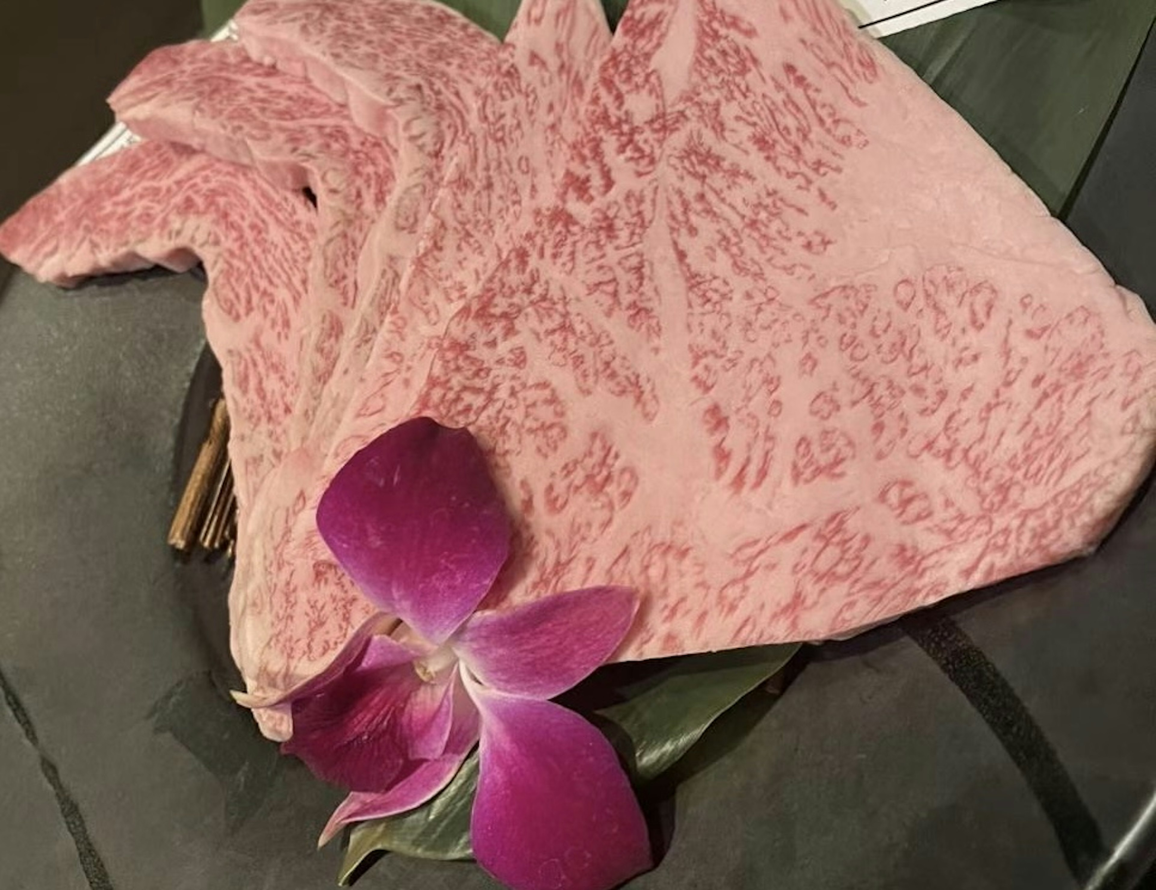 Marmorierte Wagyu-Rindfleischscheiben mit einer lila Blume