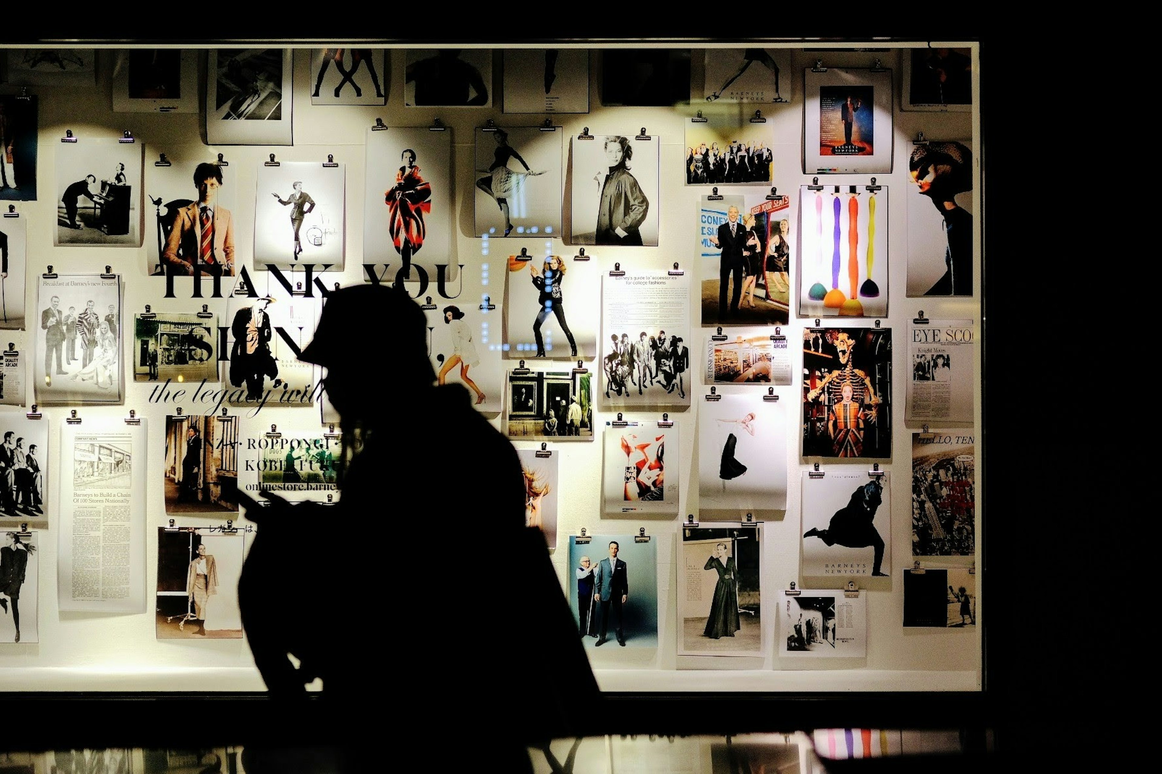 Silhouette of a person in front of a wall filled with photographs