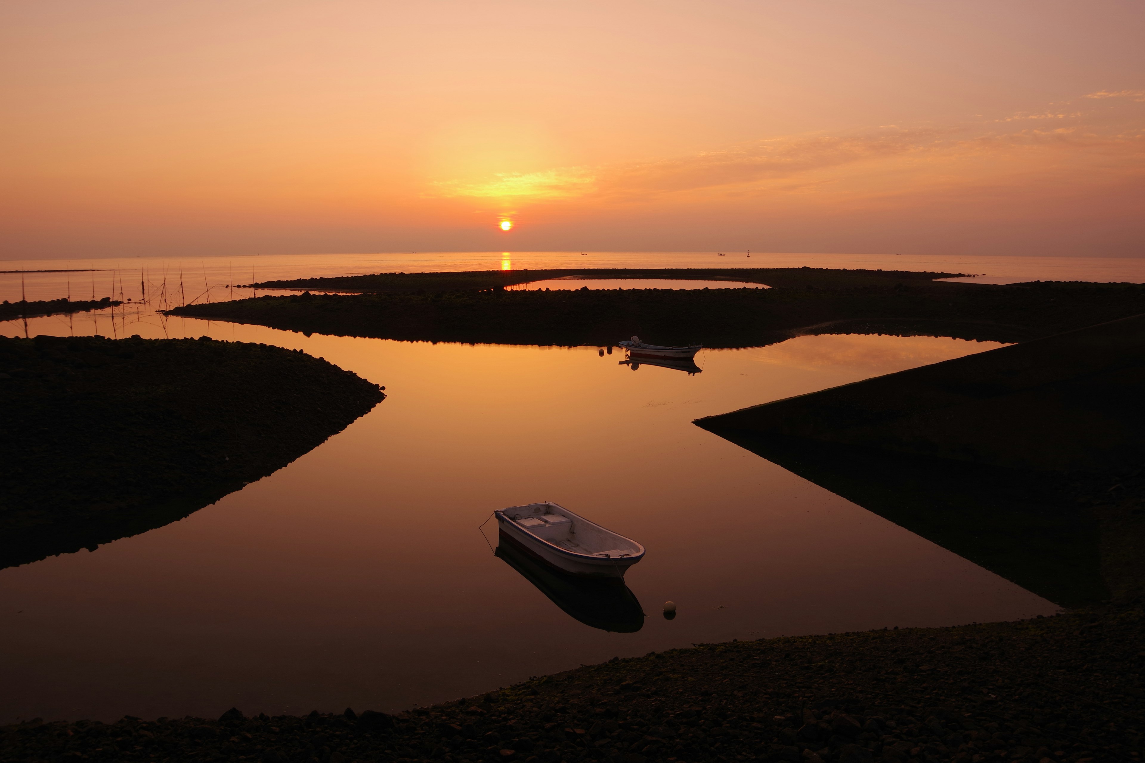 Paysage serein avec un coucher de soleil sur des eaux calmes et un petit bateau