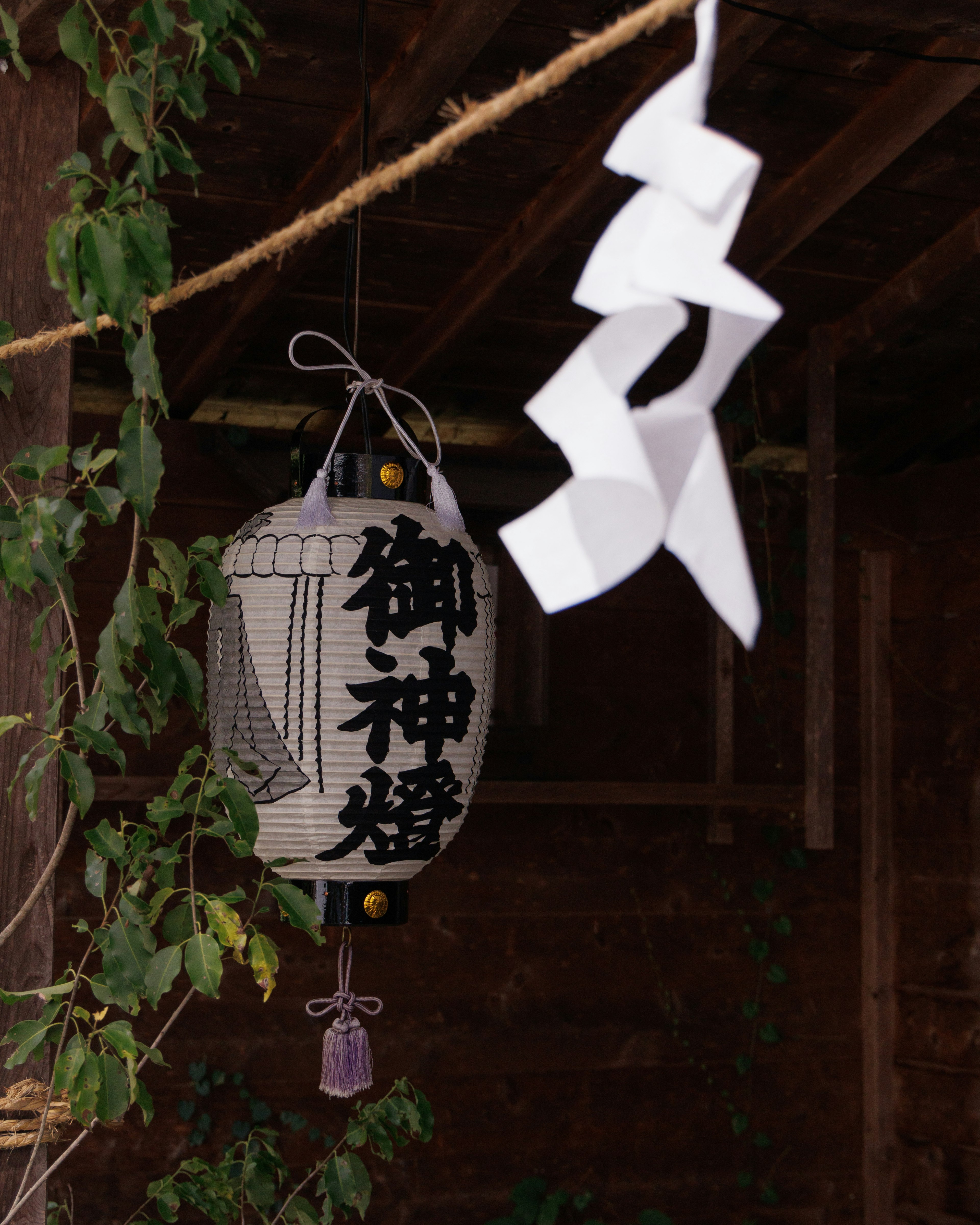 A traditional lantern with black lettering and white paper decorations hanging