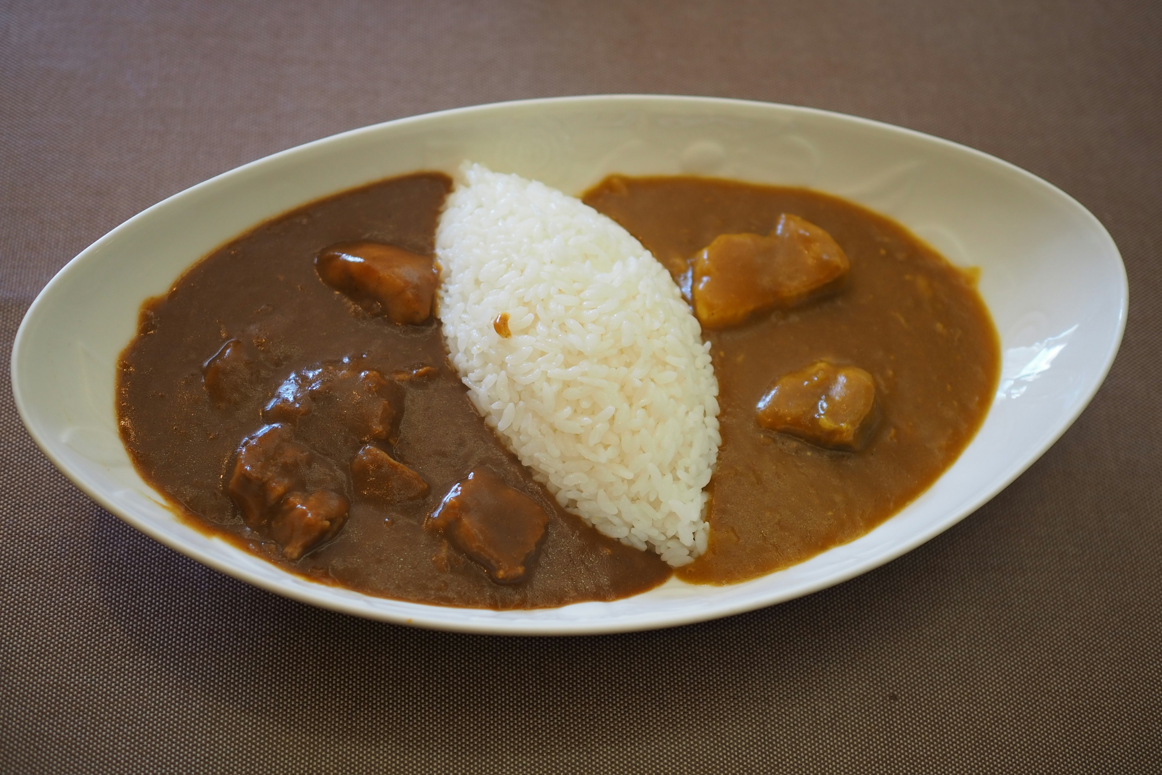 Plate of curry rice featuring a mound of rice and two types of curry