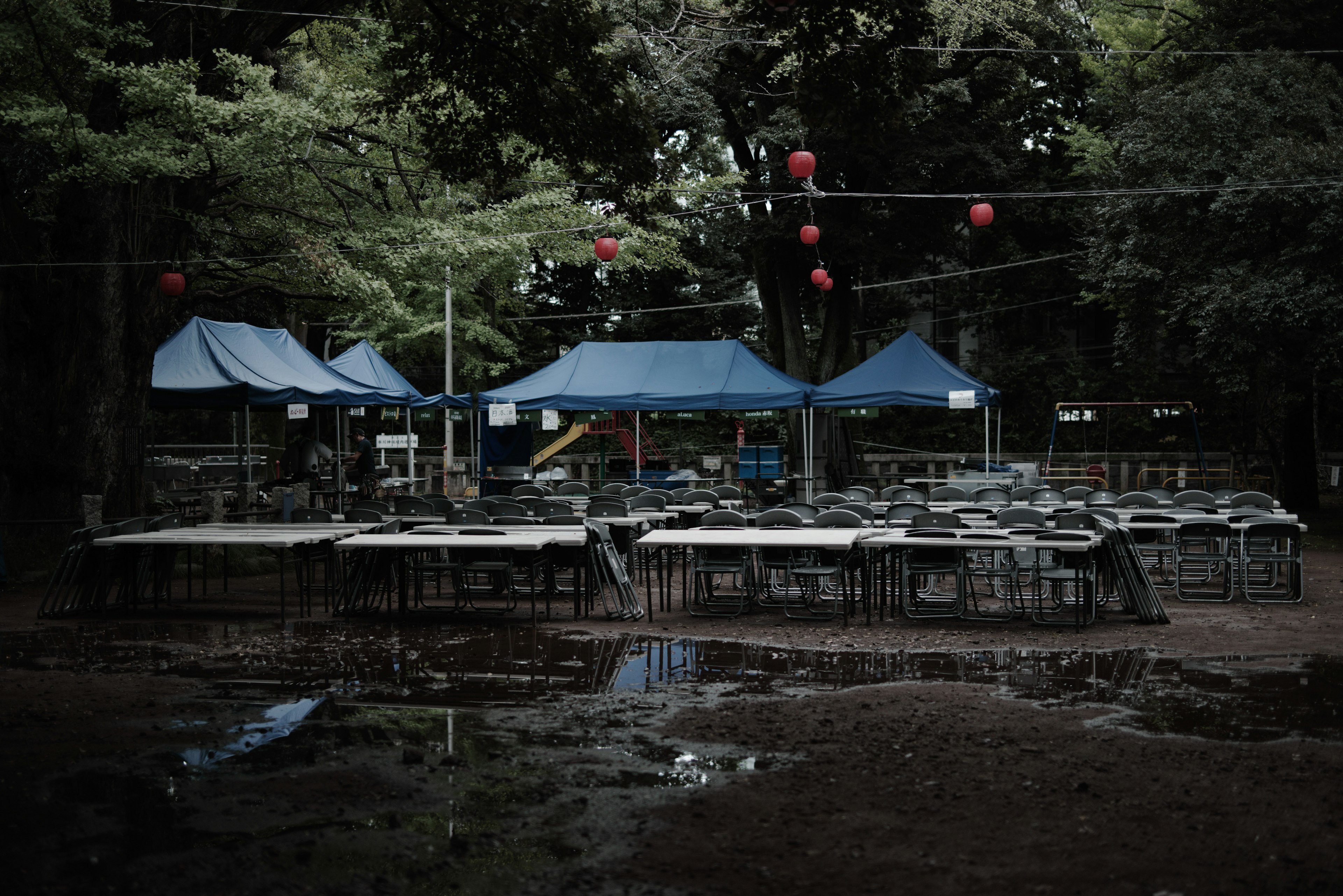 Scene with blue tents and empty tables on wet ground