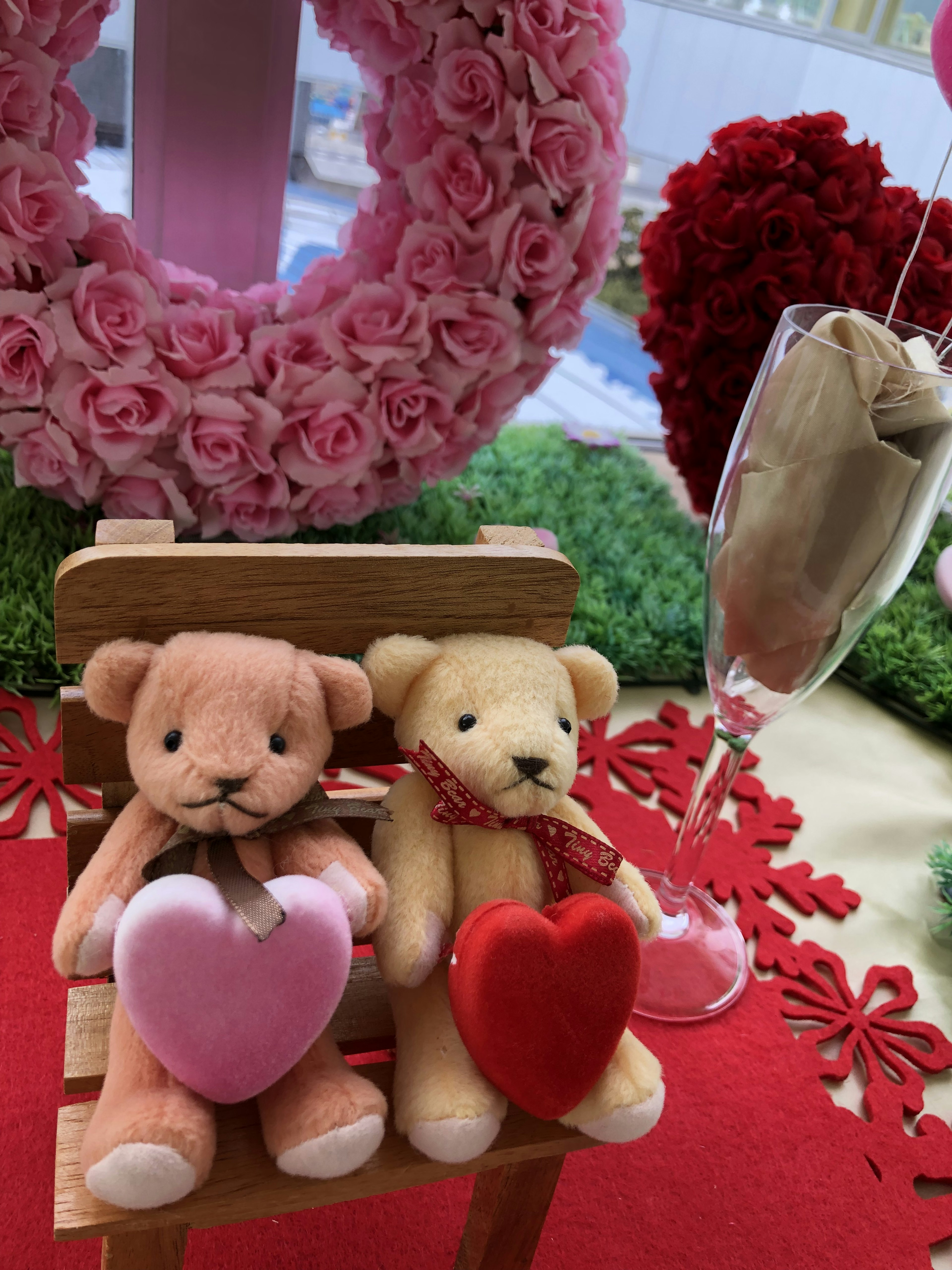 Deux ours en peluche tenant des cœurs assis sur une table rouge avec des décorations florales